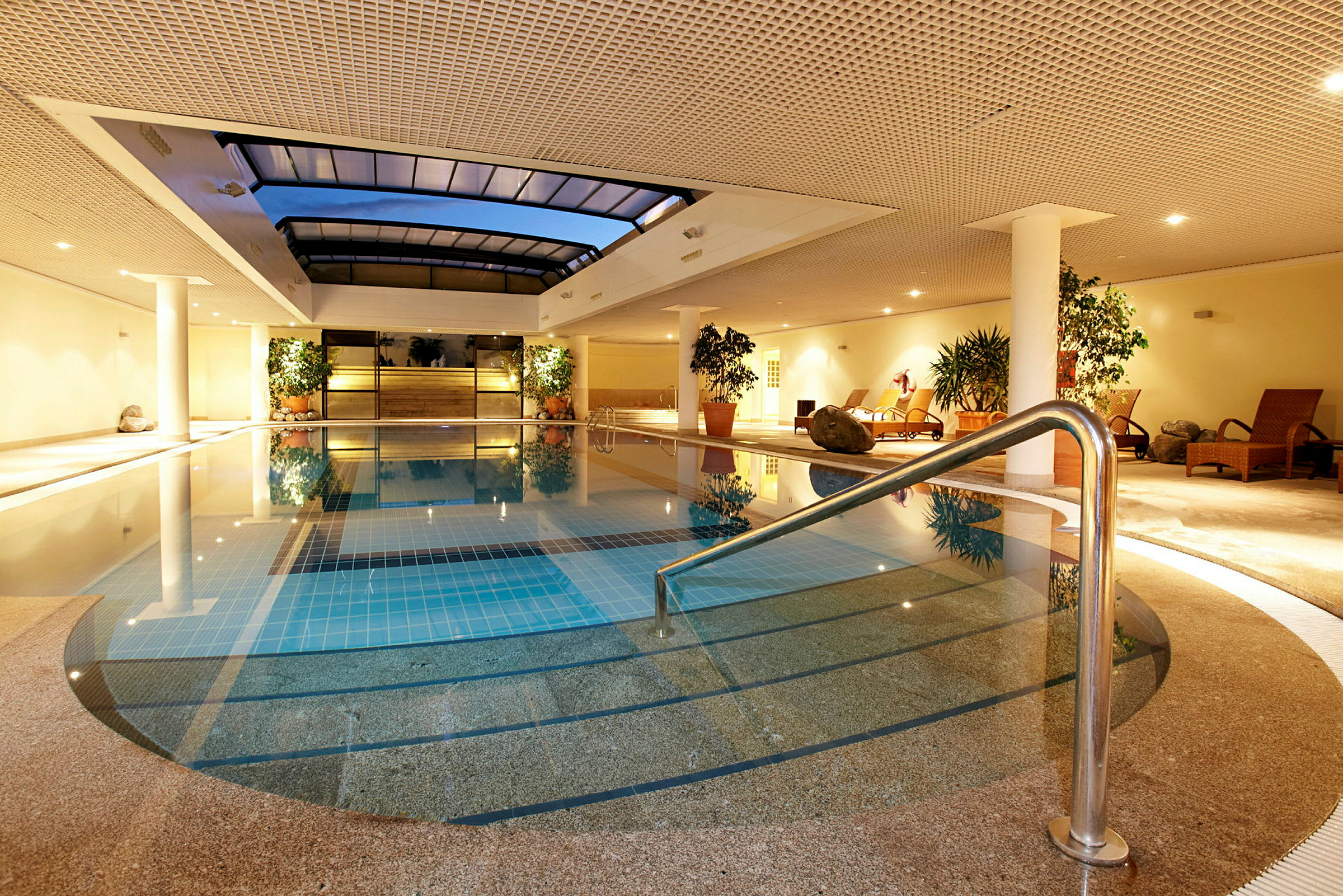 Inomhuspool med relaxområde inrett med solstolar och växter. (AI-genererad text)