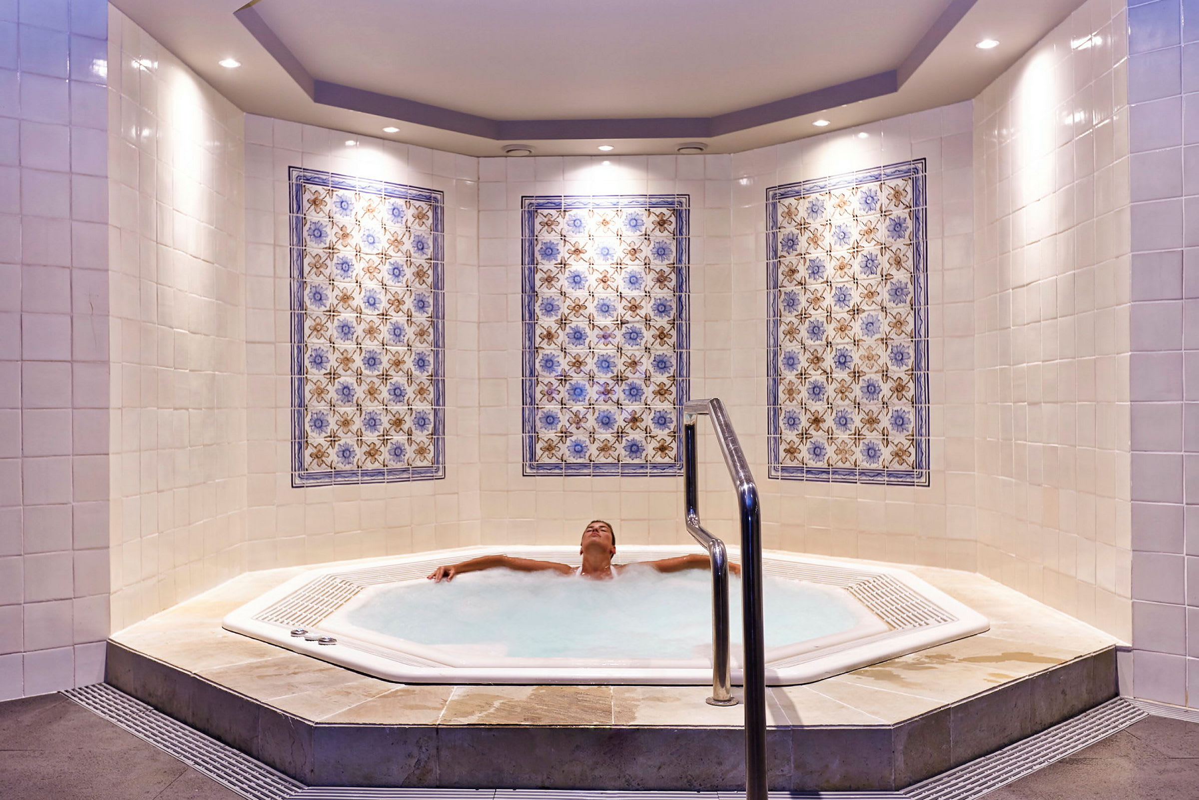 En jacuzzi med mosaikdetaljer på väggarna. (AI-genererad text)