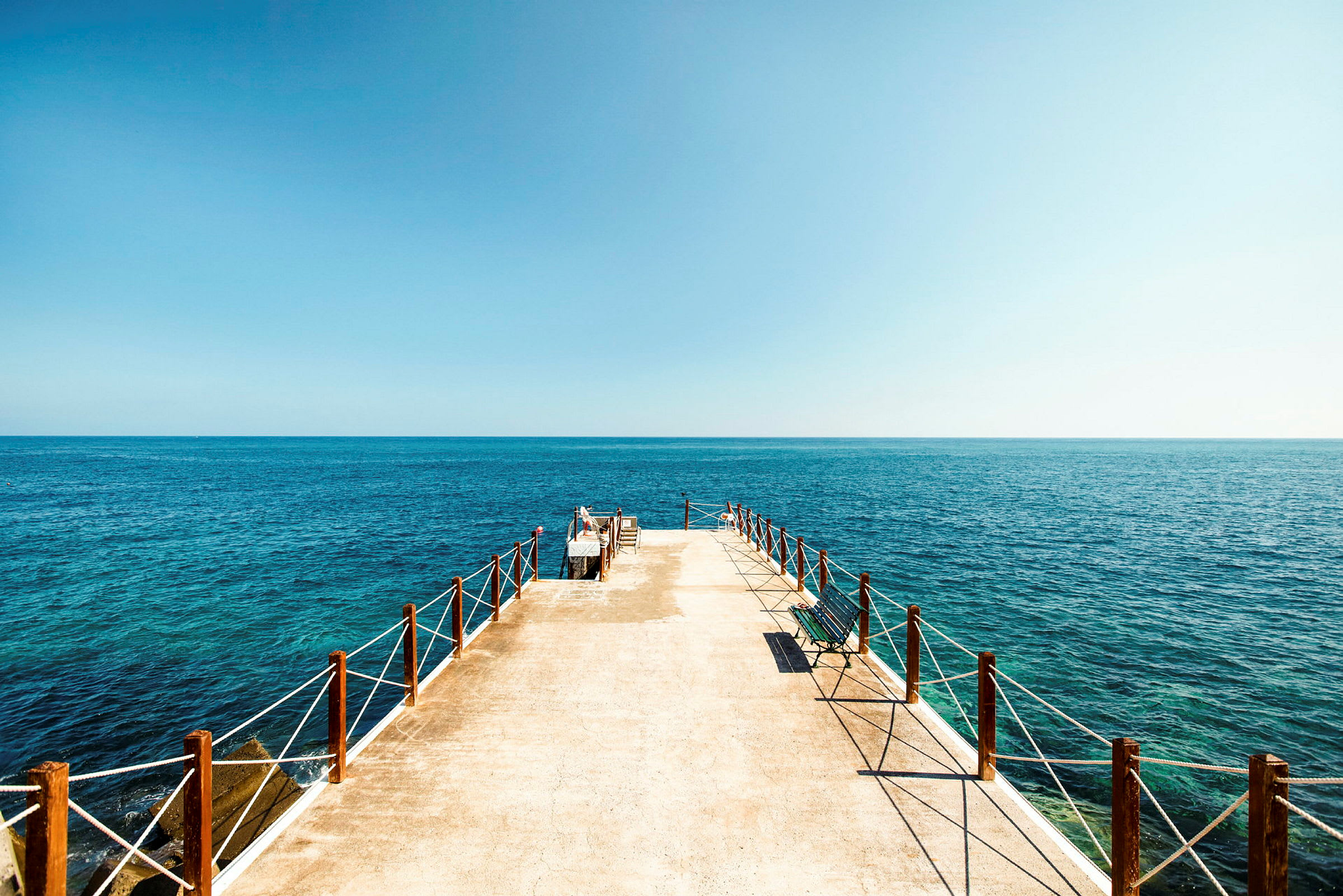 En brygga som leder ut i havet under en klar himmel. (AI-genererad text)