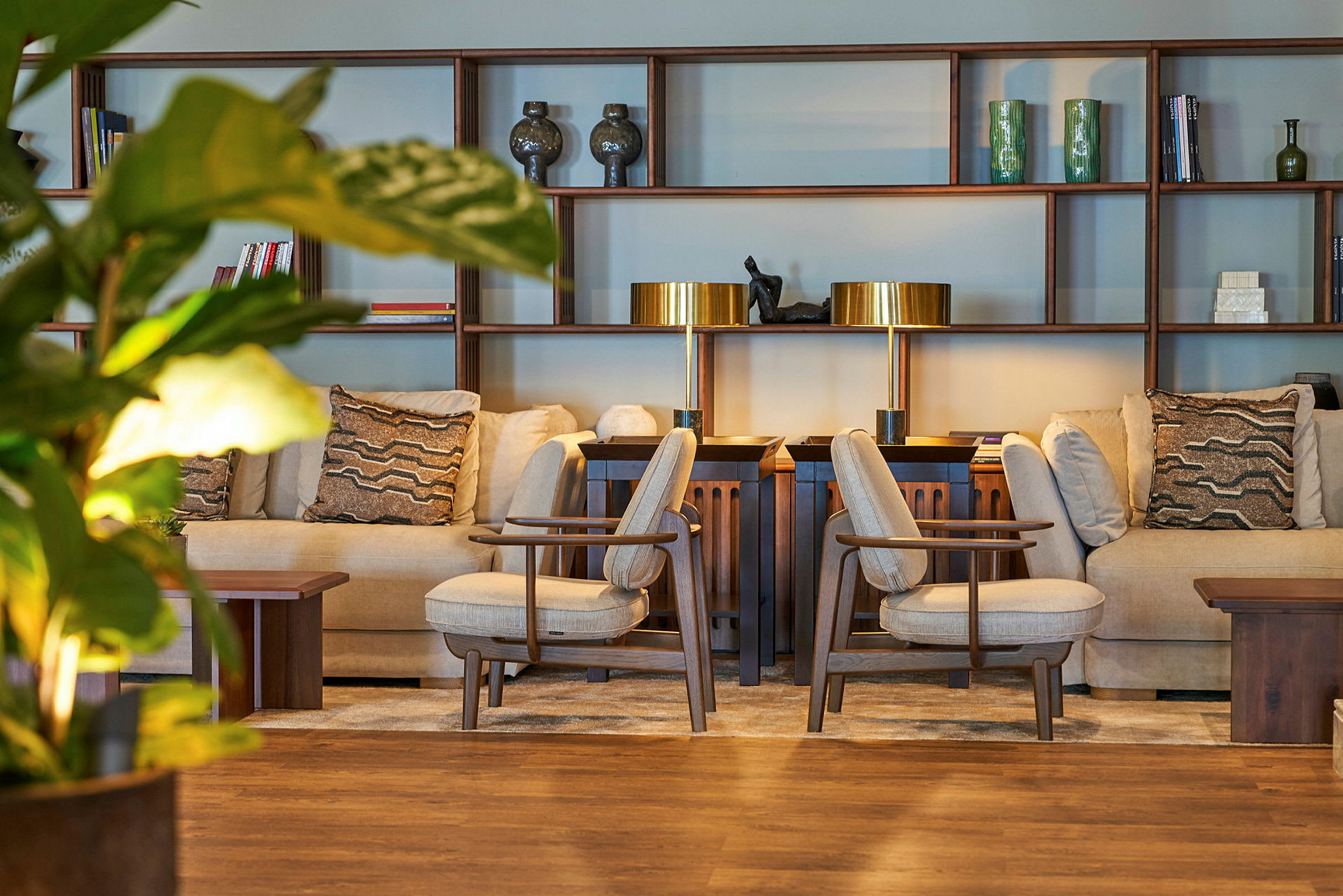 En lounge med fåtöljer och soffor framför en träbokhylla. (AI-genererad text)