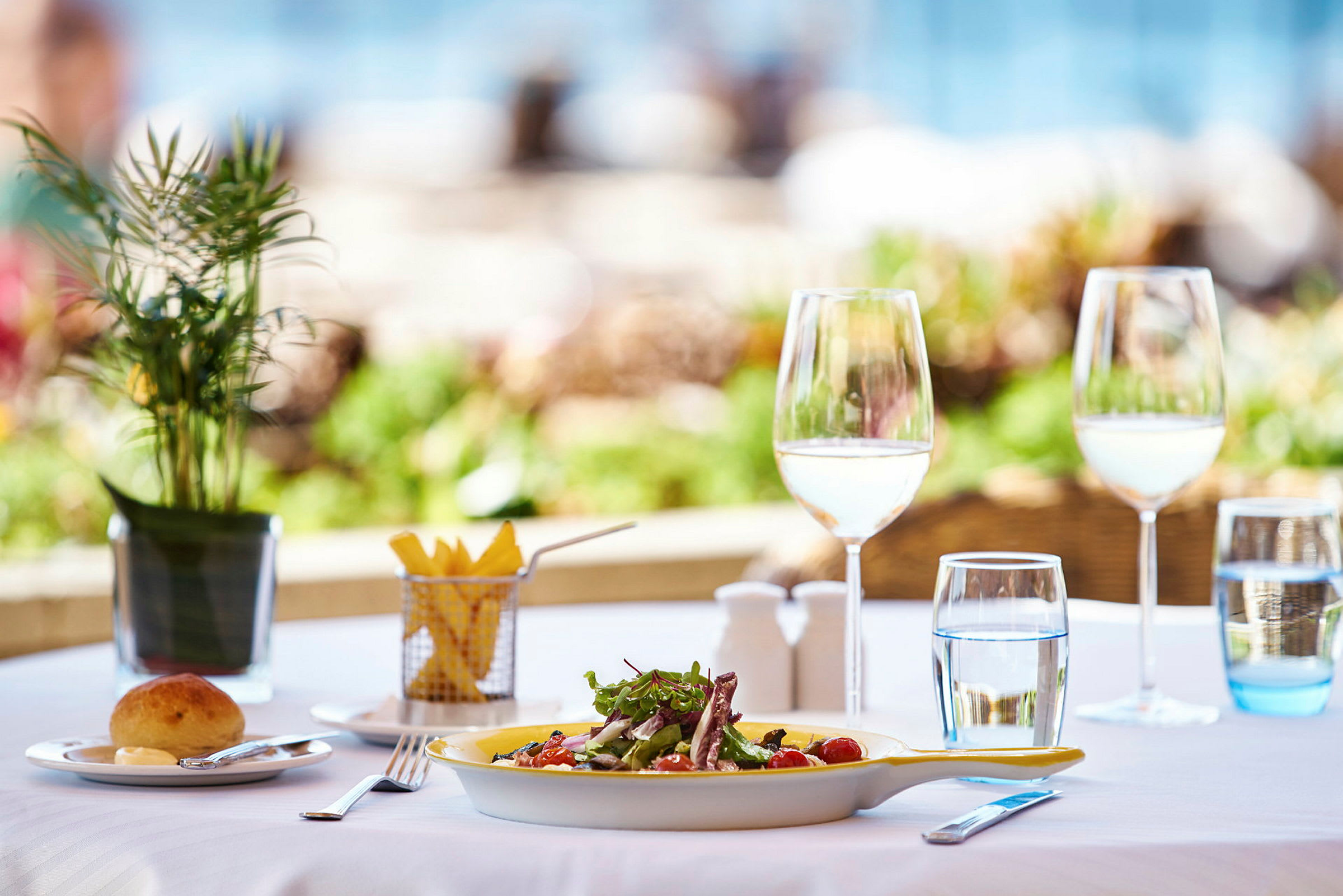 Ett bord med dukade tallrikar, glas och en sallad. (AI-genererad text)
