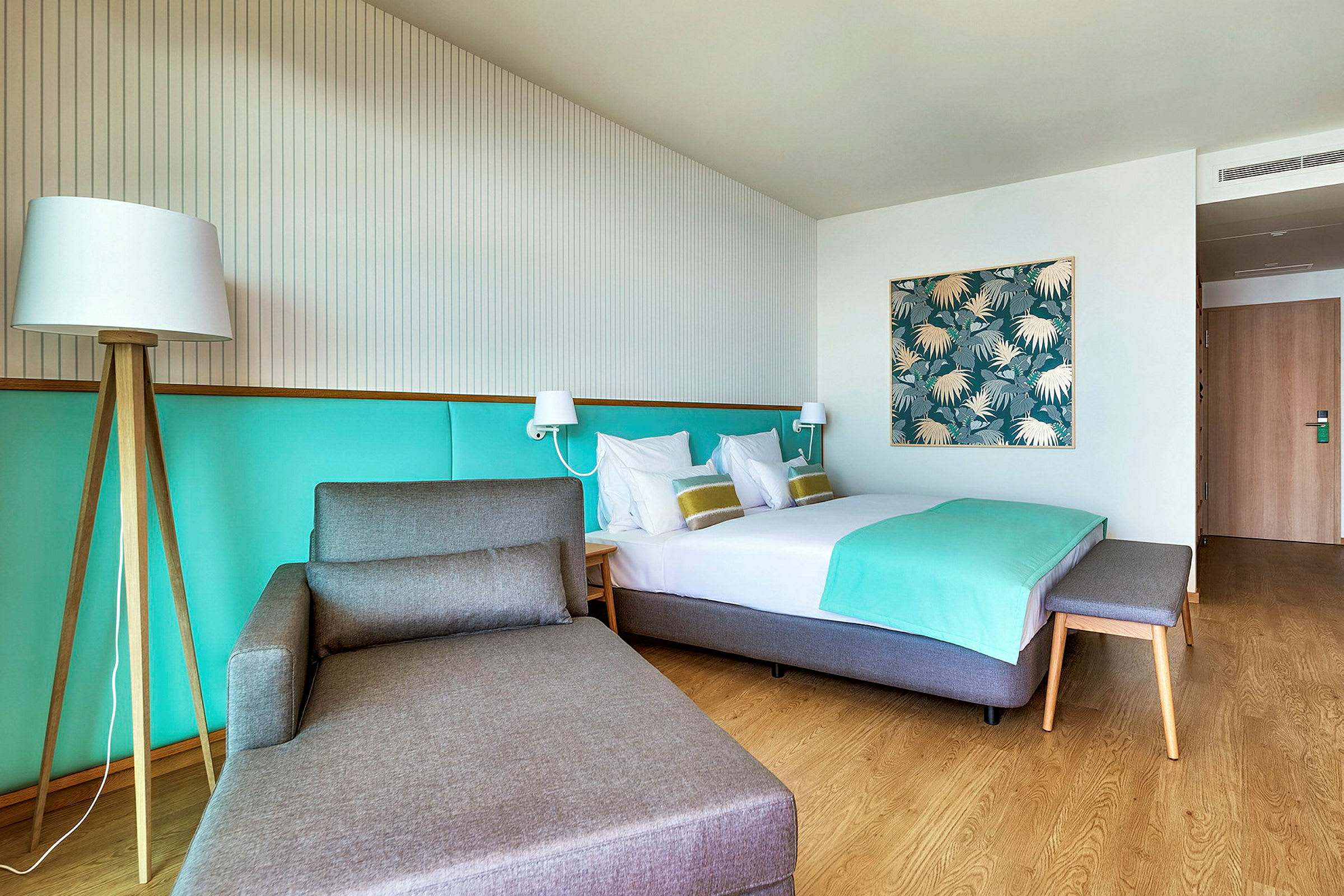 Hotellrum med en säng, en sittmöbel och ljus dekor. (AI-genererad text)