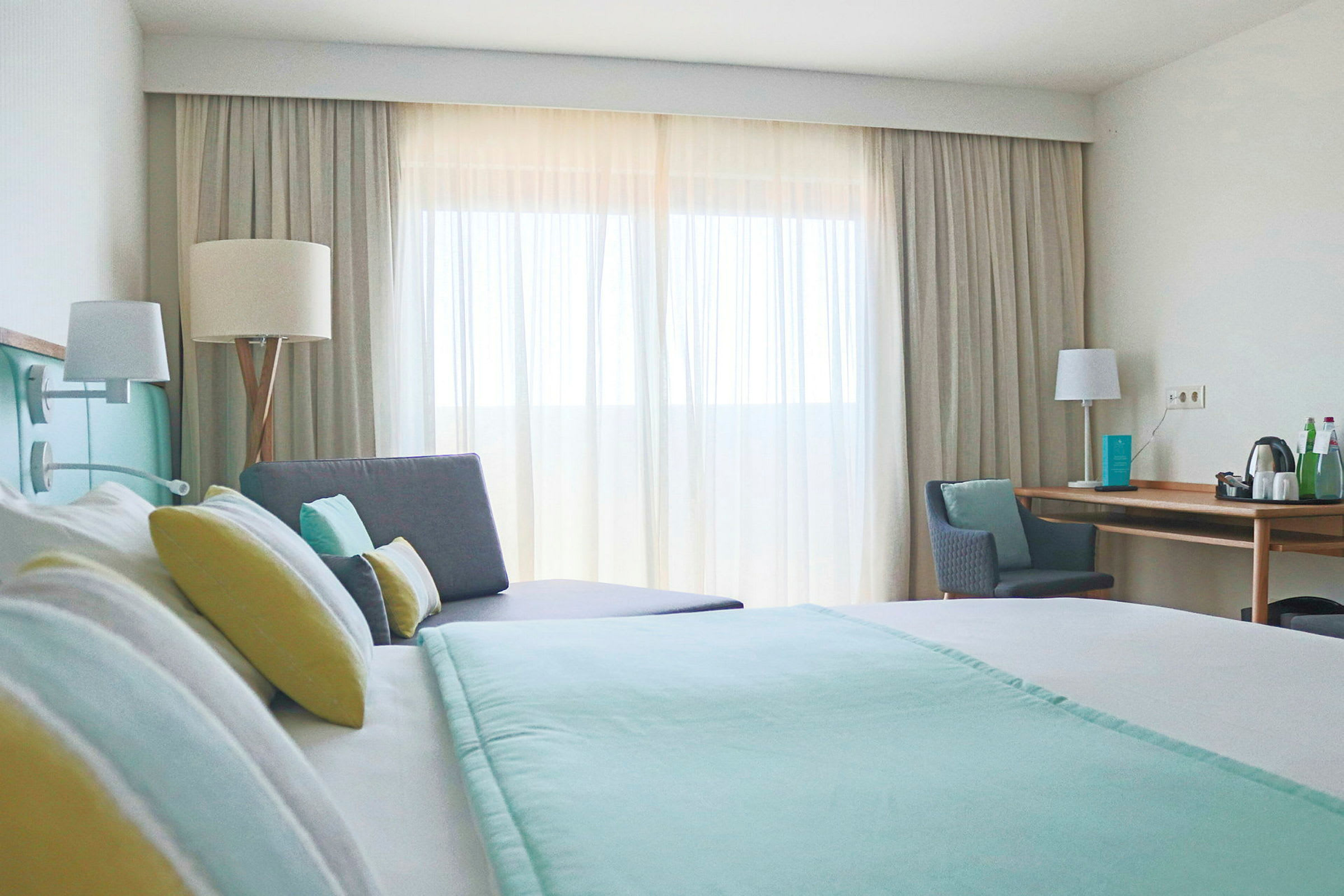 Modernt hotellrum med en dubbelsäng, soffa och skrivbord. (AI-genererad text)