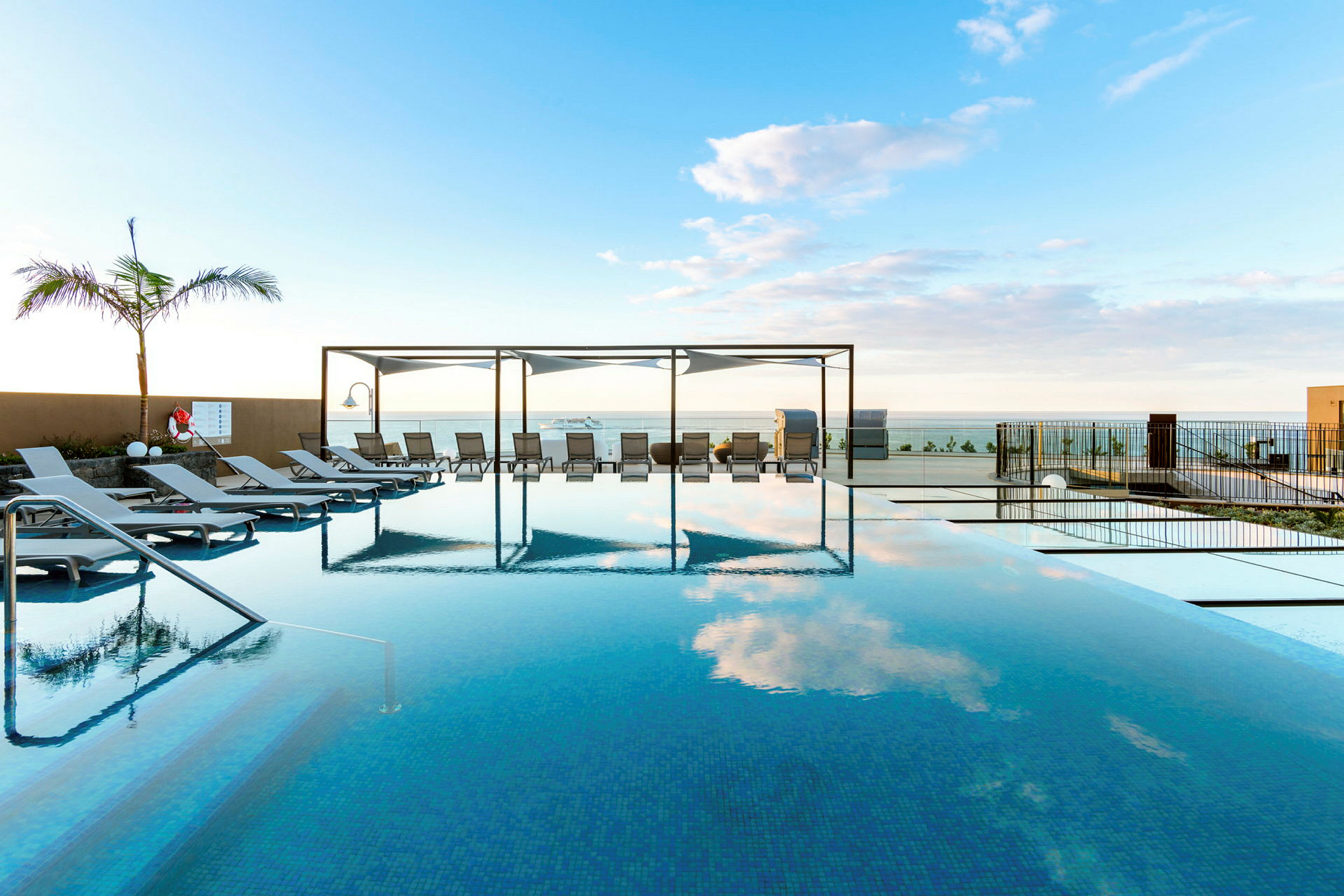 En infinitypool med solstolar och utsikt över havet. (AI-genererad text)