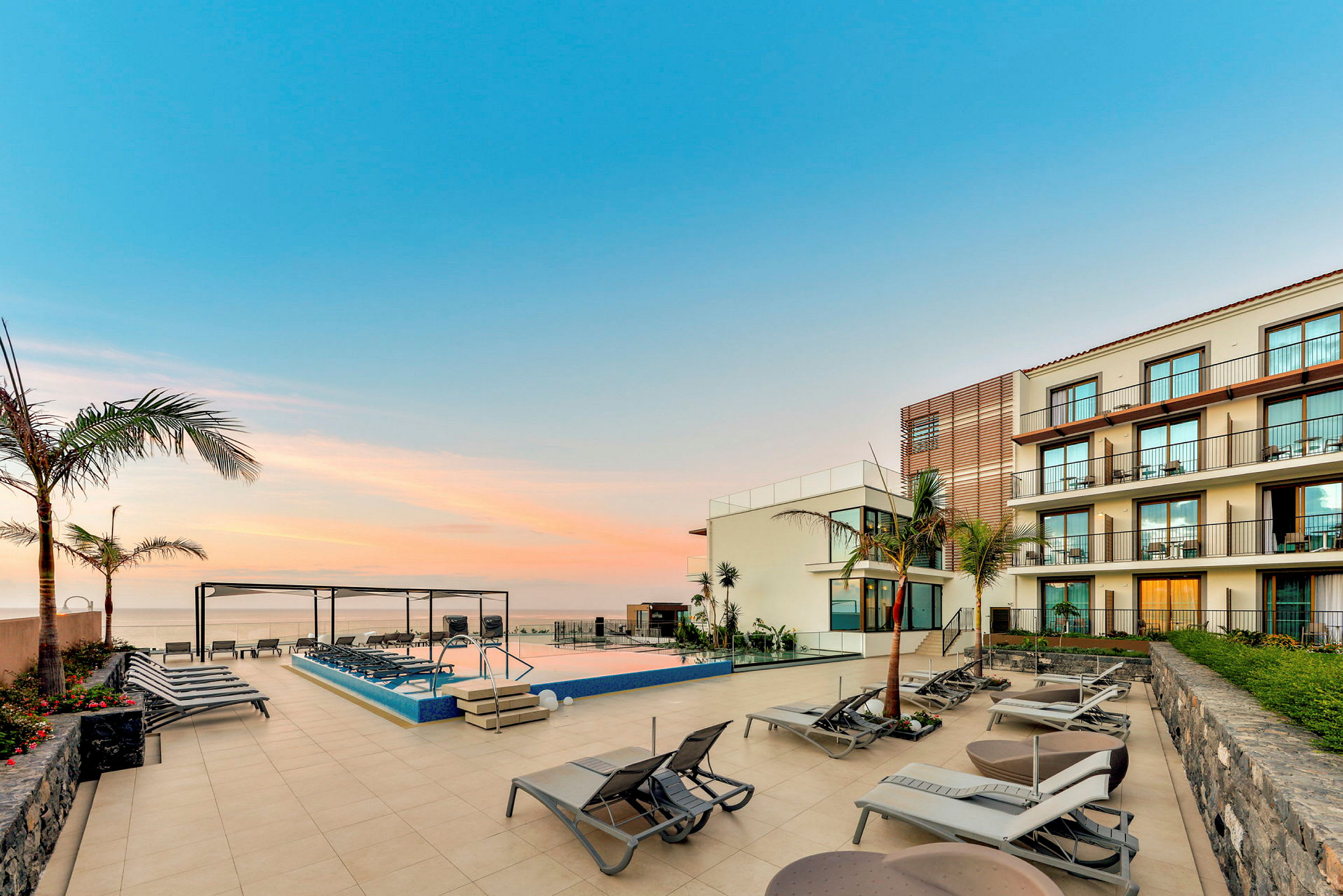 Solstolar vid en pool med hotellbyggnad i bakgrunden. (AI-genererad text)
