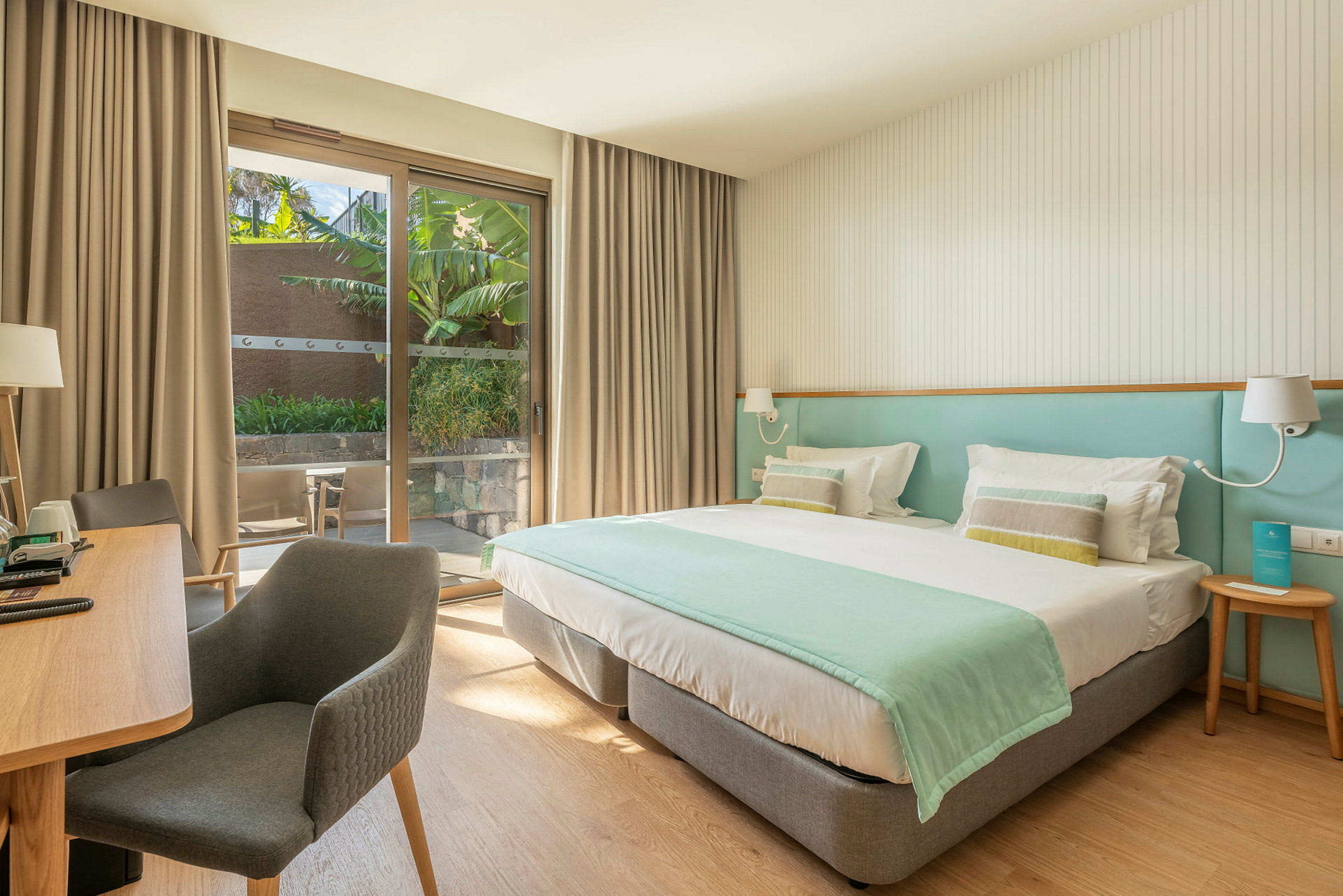 Hotellrum med dubbelsäng, skrivbord och sittplats. Skjutdörrar leder ut till en privat terrass. (AI-genererad text)