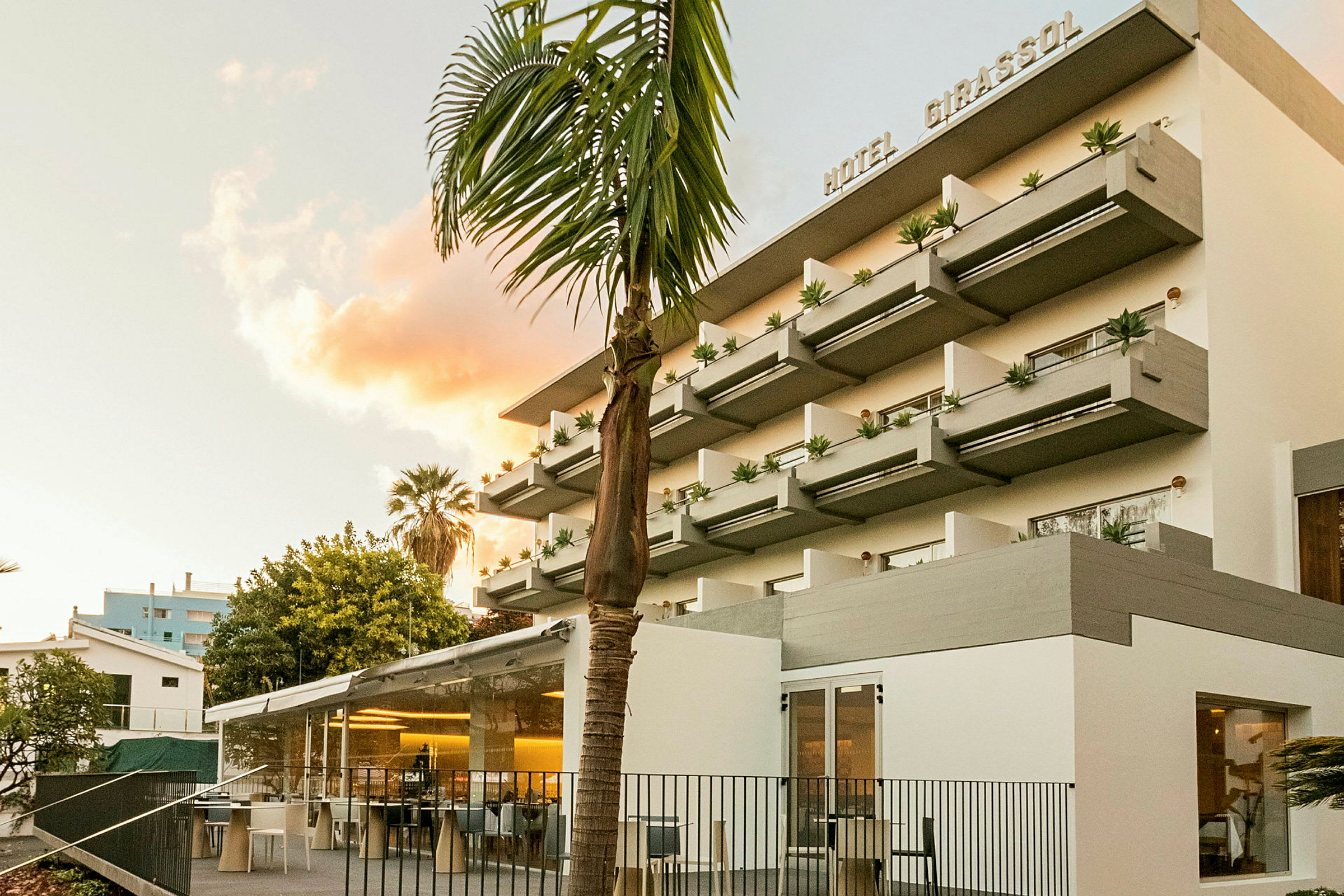 Hotellfasad med moderna balkonger och träd i förgrunden. (AI-genererad text)