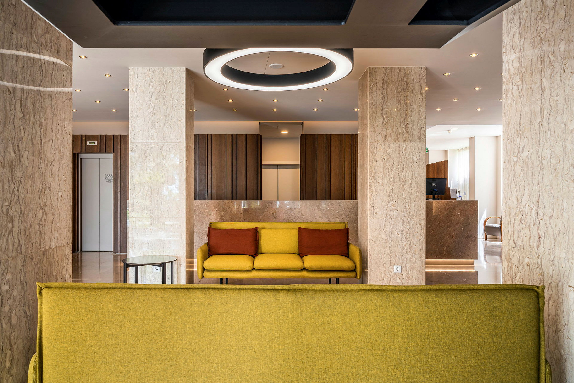 Modernt hotellobby med gula soffor och marmorväggar. (AI-genererad text)