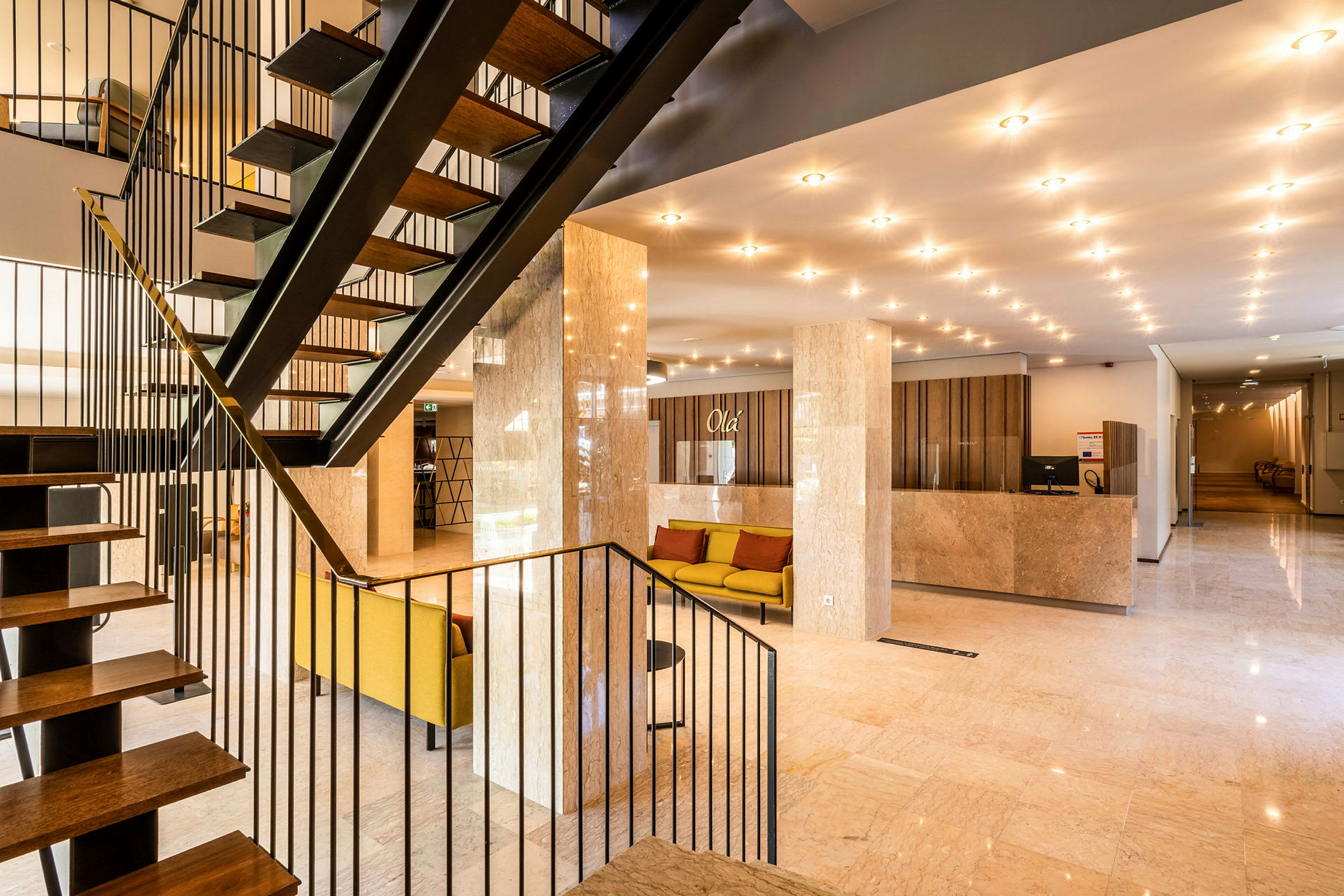 Hotellobby med en trappa, sittmöbler och receptionsdisk. (AI-genererad text)