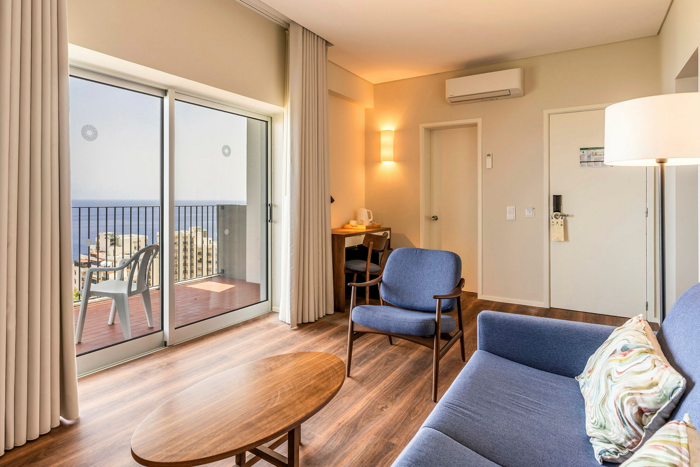Modernt hotellrum med sittplatser och utsikt över havet genom stora fönster. (AI-genererad text)