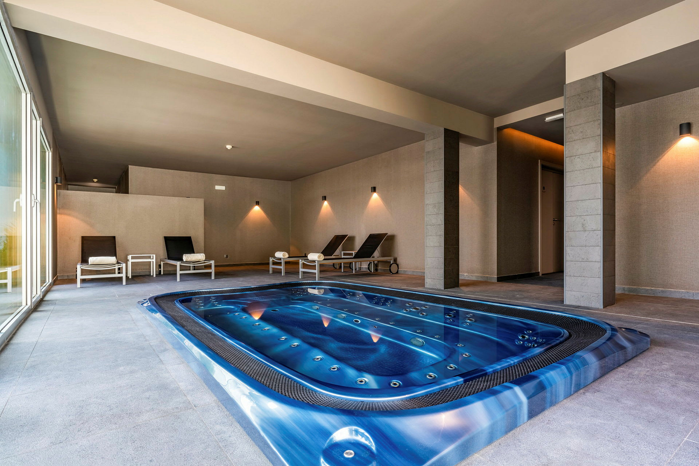 Inomhus jacuzzi med vilstolar och grå väggar. (AI-genererad text)