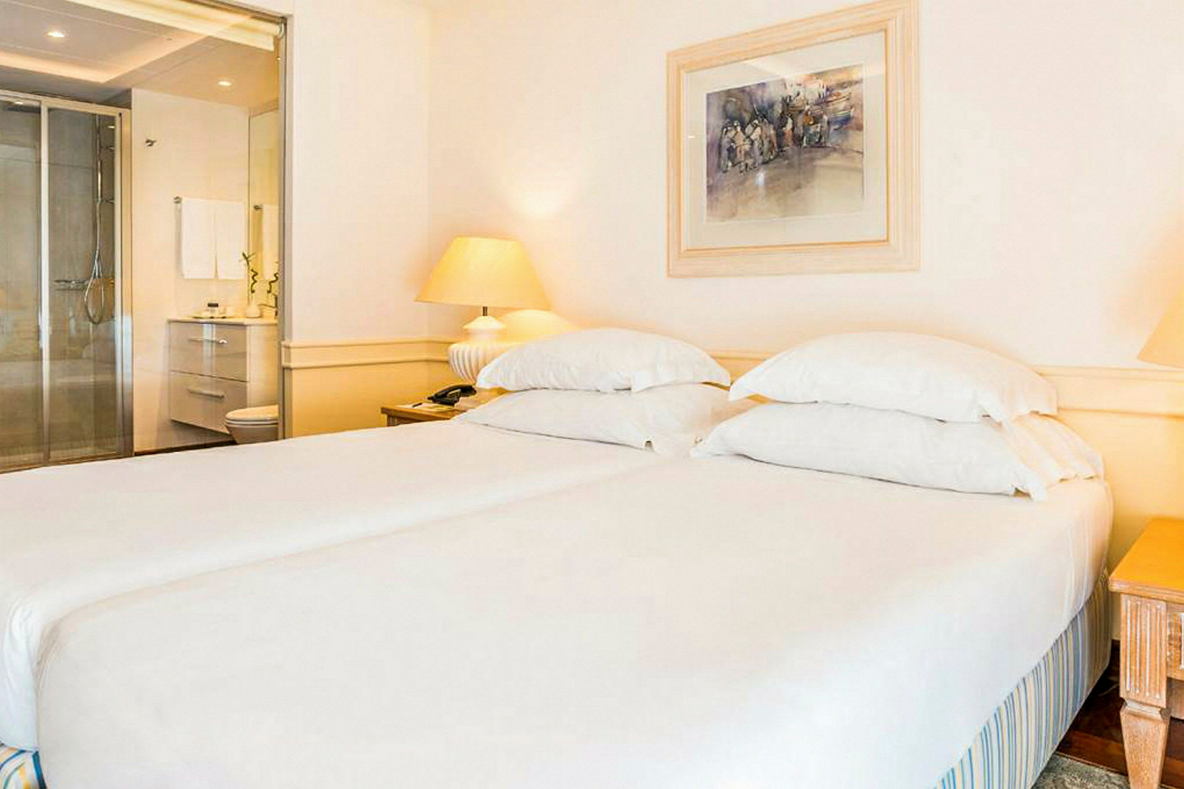 Två sängar med vita sängkläder i ett hotellrum. (AI-genererad text)