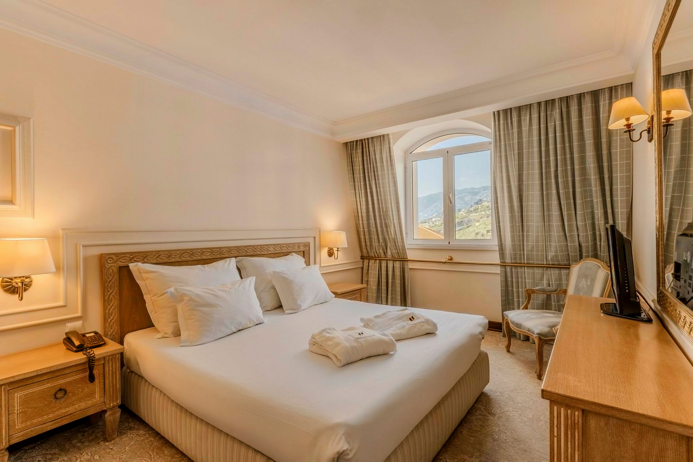 Ett hotellrum med en dubbelsäng, nattduksbord och ett fönster med utsikt. (AI-genererad text)