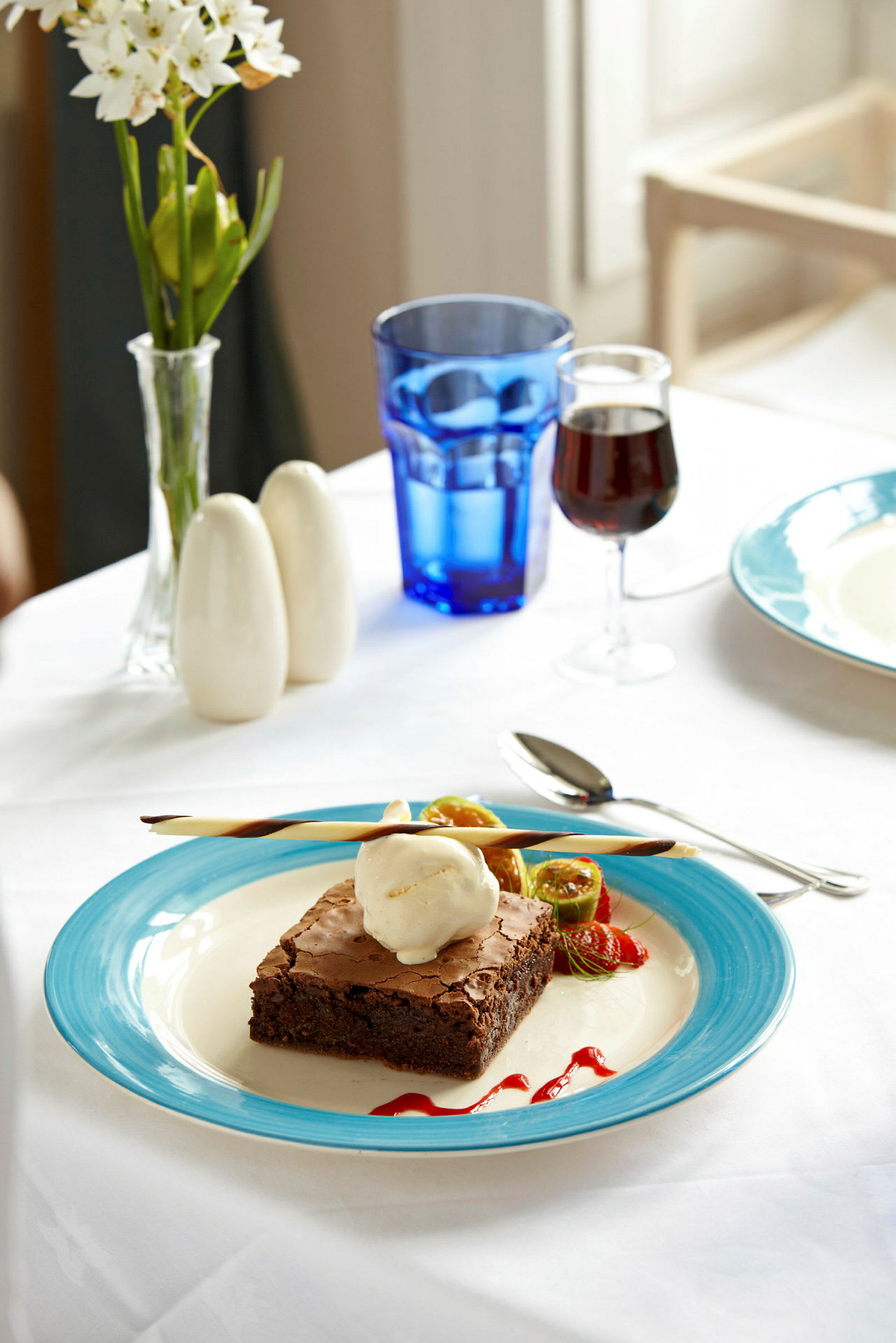 En tallrik med brownie och glass, dekorerad med frukt och sås. (AI-genererad text)