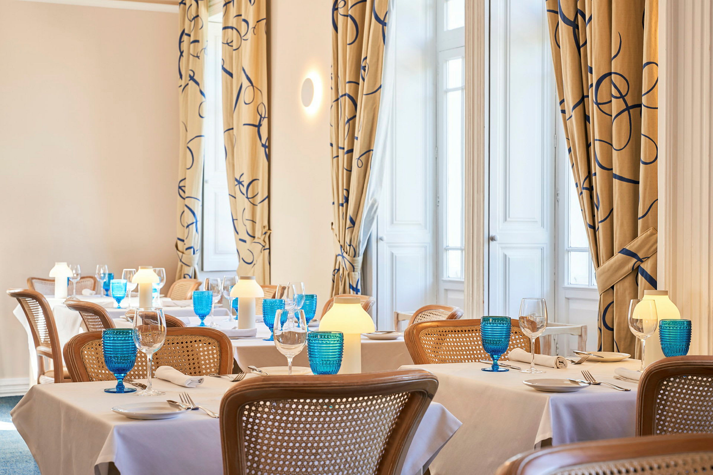 Bild av en elegant restaurang med dukade bord, blå glas och varm belysning. (AI-genererad text)