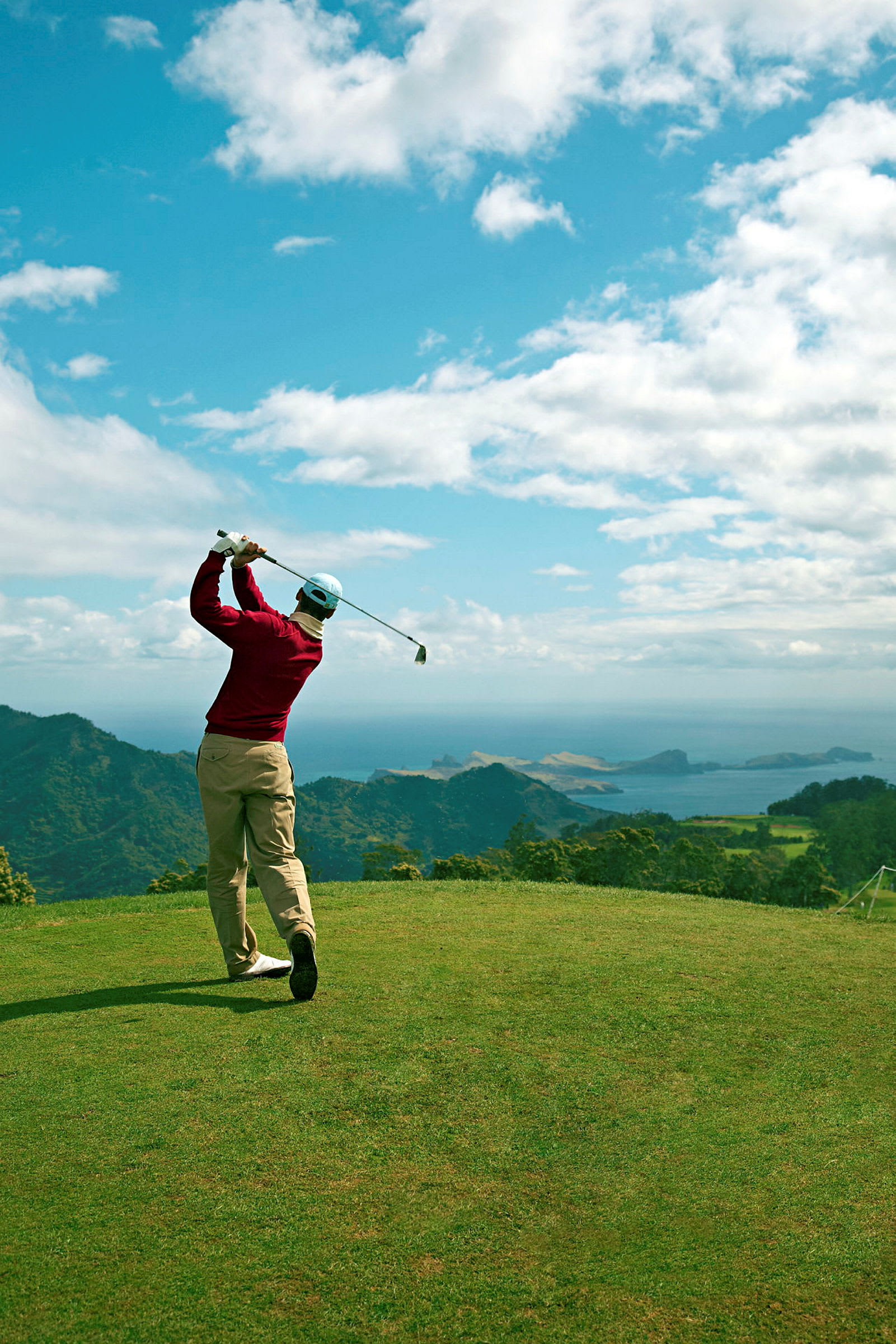 En person spelar golf på en bana med utsikt över kust och hav. (AI-genererad text)