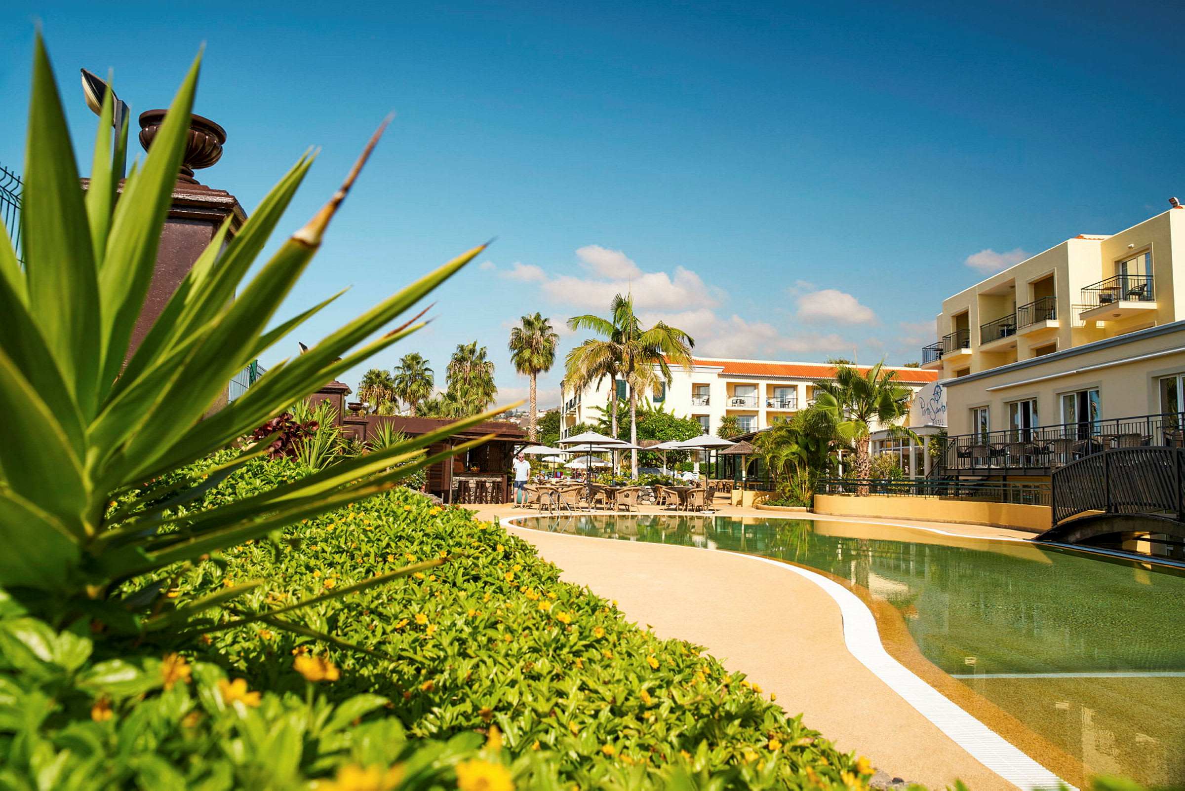 Bild av ett hotellområde med en pool, solstolar och grönska. (AI-genererad text)