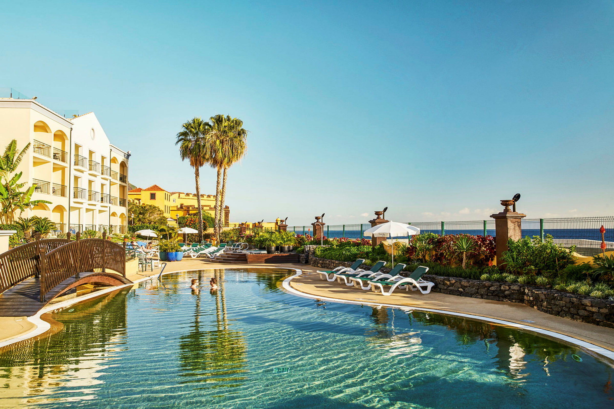 Hotell med pool, solstolar och palmträd vid kusten. (AI-genererad text)