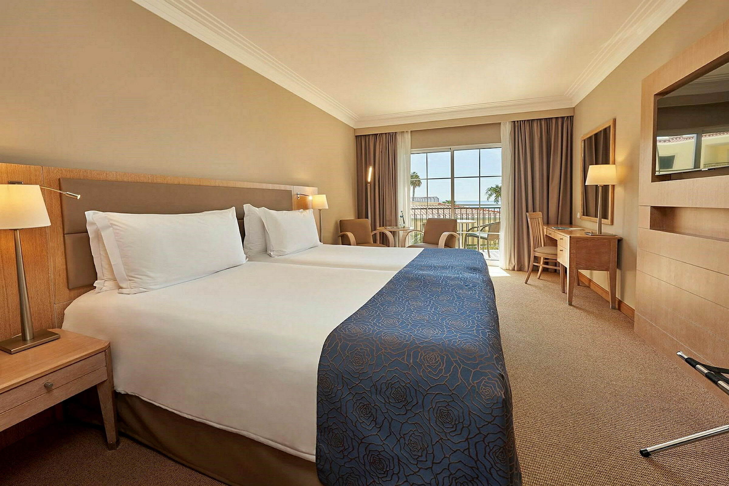 Hotellrum med två enkelsängar och en balkong med utsikt. (AI-genererad text)