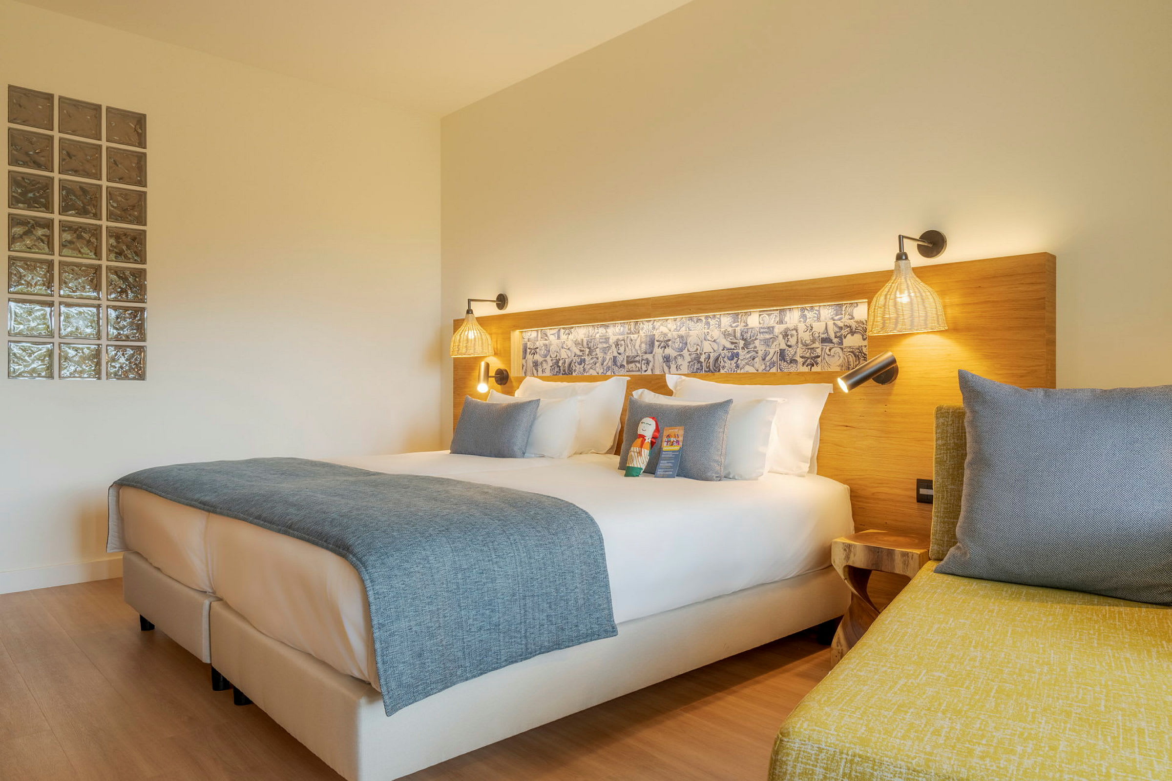 Modern hotellrum med dubbelsäng, vita sängkläder och blå överkast. (AI-genererad text)