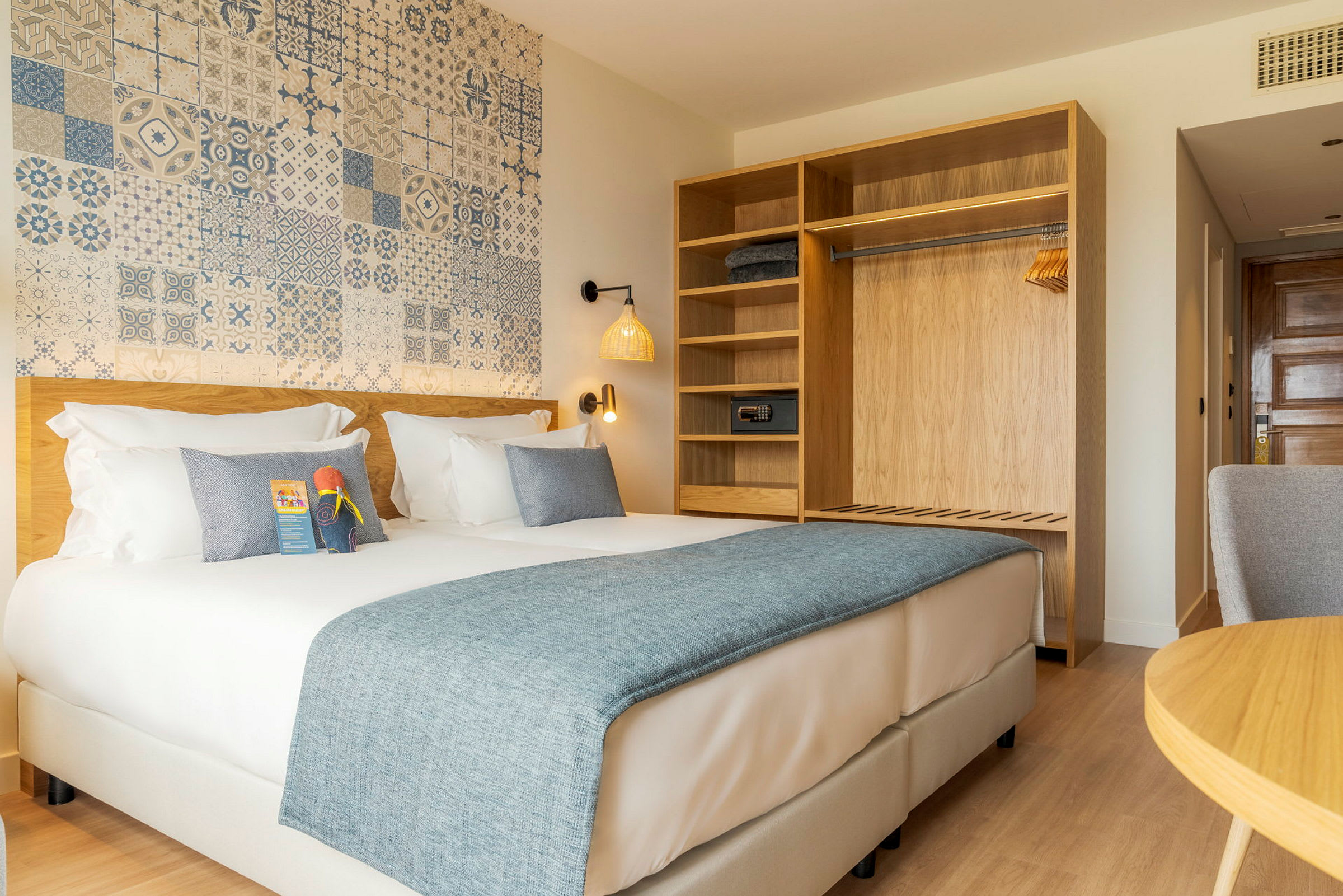 Ett hotellrum med en dubbelsäng, en garderob med hyllor och en dekorerad vägg. (AI-genererad text)