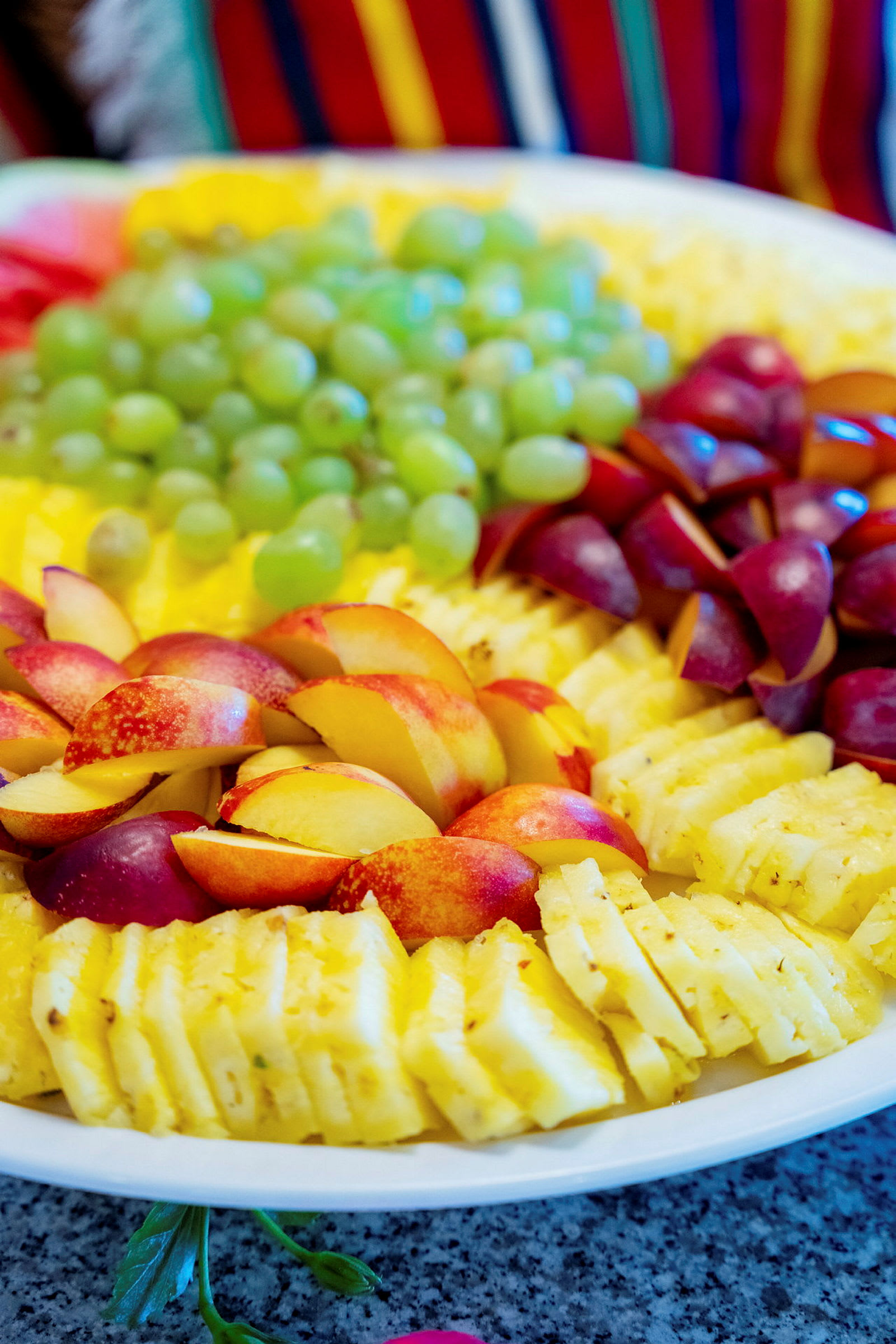 En tallrik med skivad ananas, druvor, nektariner och röda frukter. (AI-genererad text)