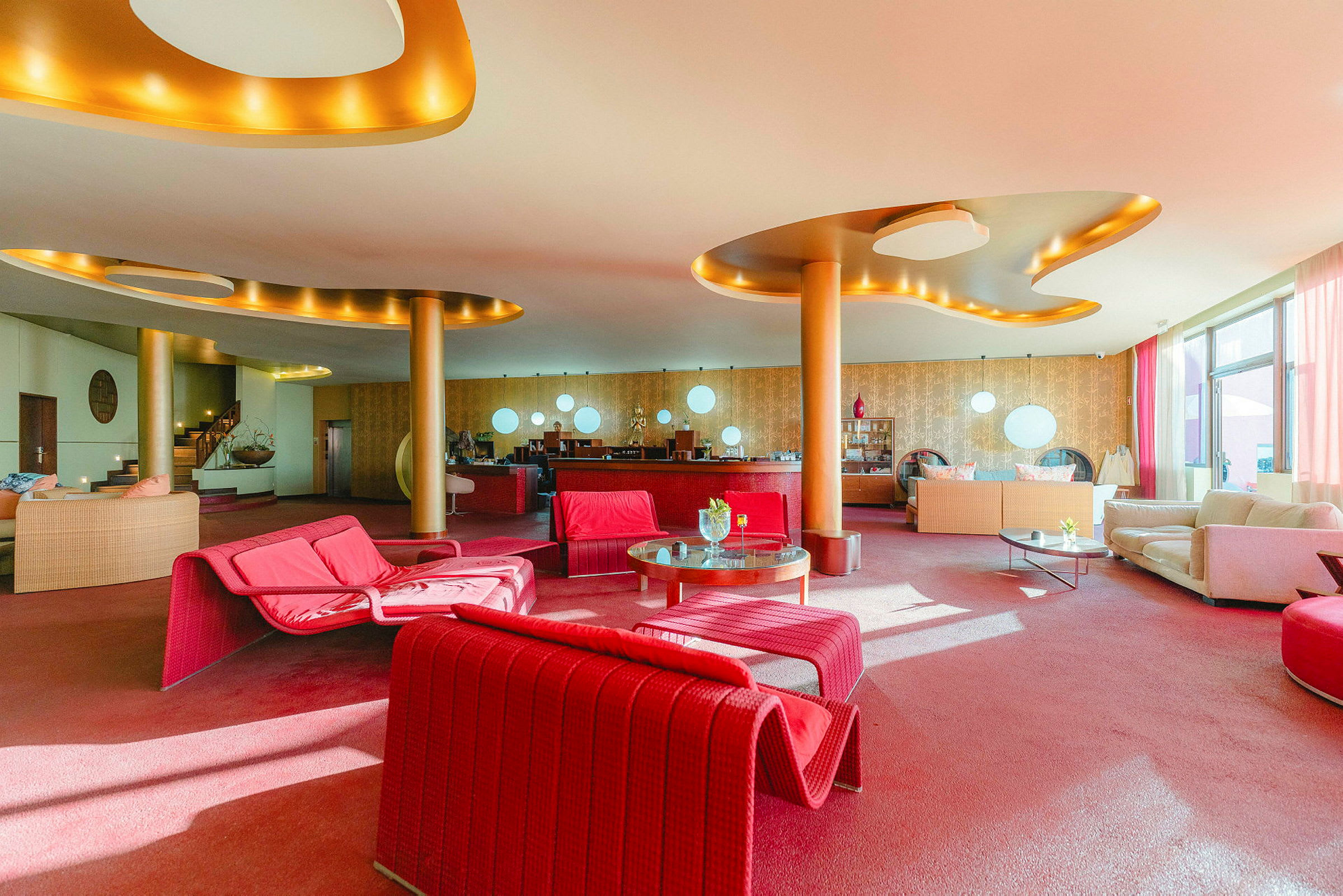 En hotellobby med färgglada möbler, främst röda och beige. Det finns soffor, bord och moderna inredningsdetaljer. (AI-genererad text)