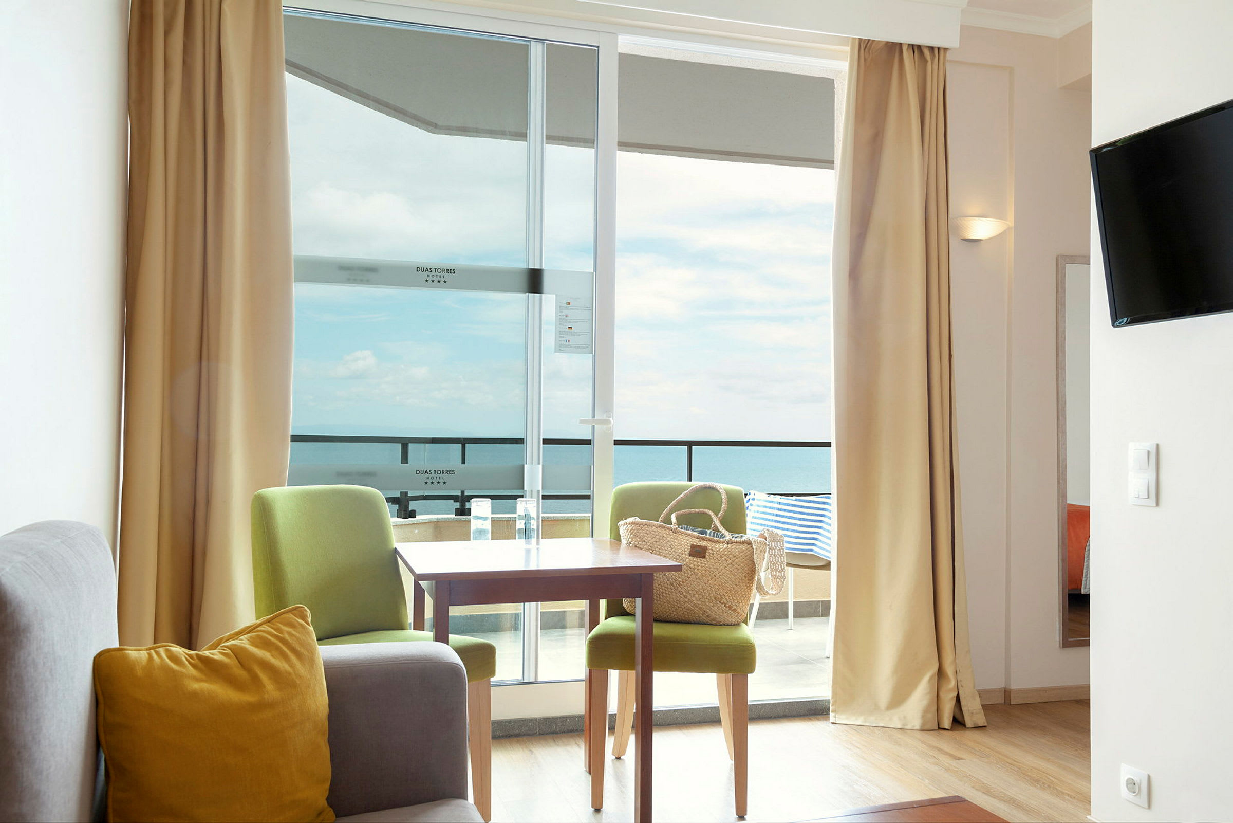 Ett hotellrum med sittgrupp och utsikt mot havet. (AI-genererad text)