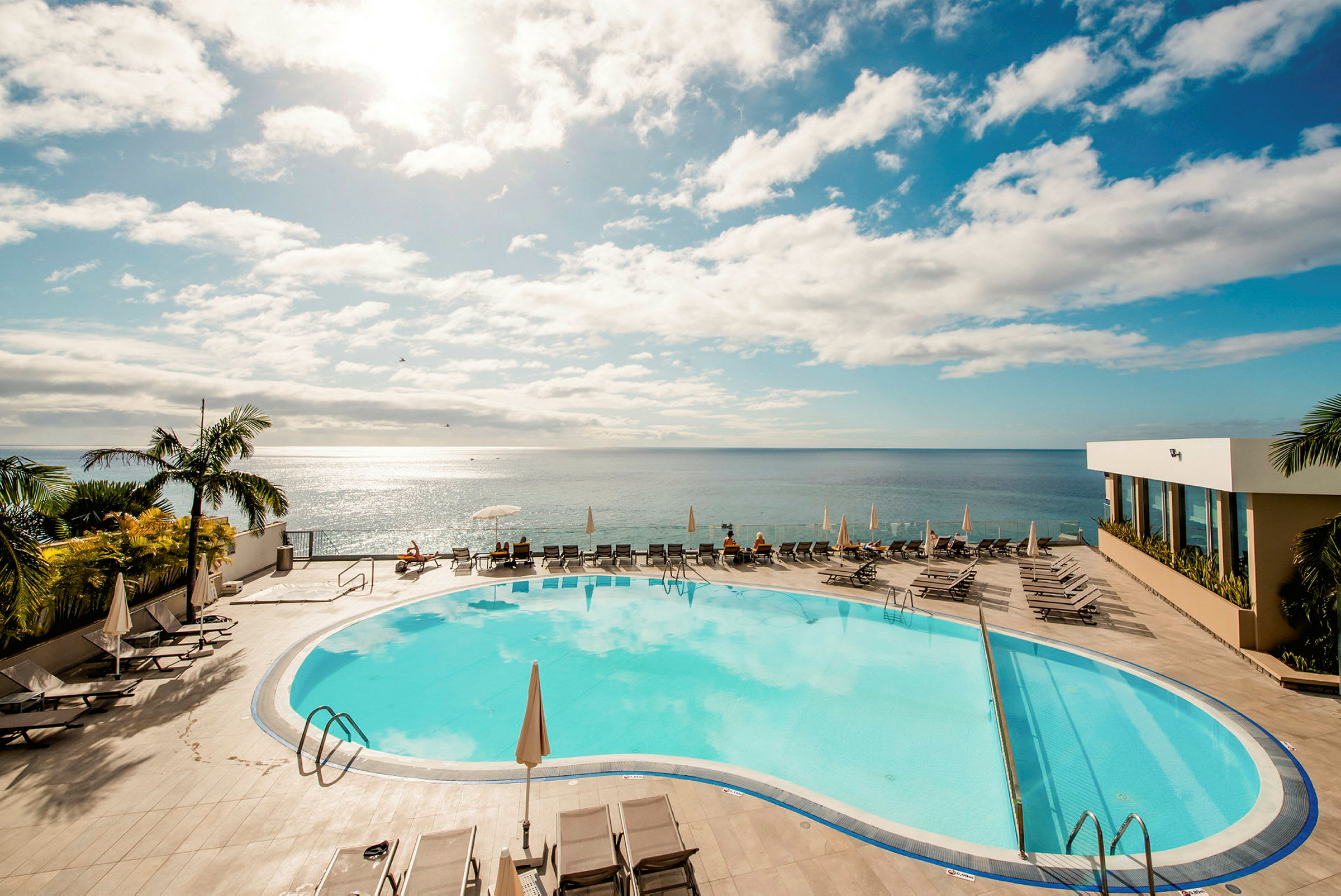 Poolområde med utsikt över havet under en klar himmel. (AI-genererad text)