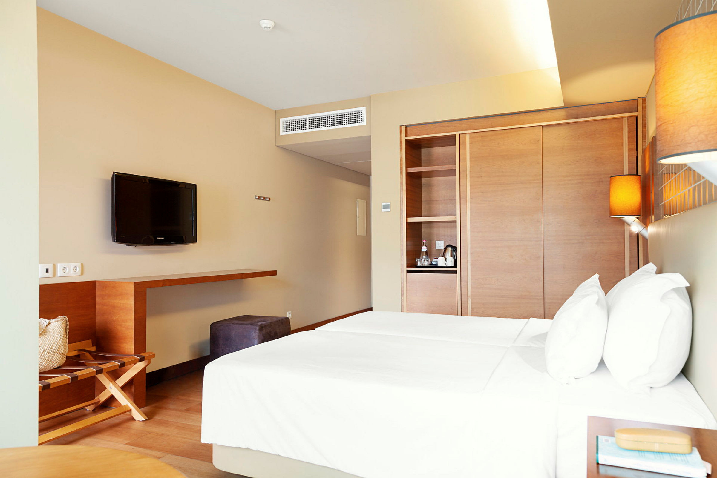 Hotellrum med två sängar, TV och förvaringsutrymme. (AI-genererad text)