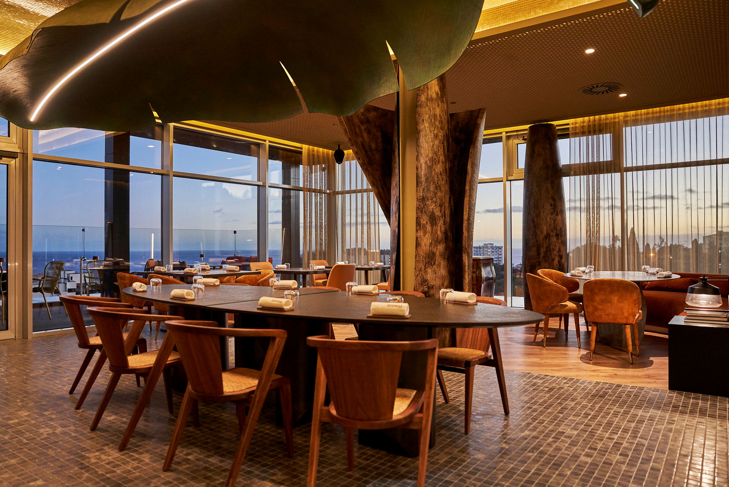 Bord och stolar i en modern restaurang med stora glasfönster. (AI-genererad text)