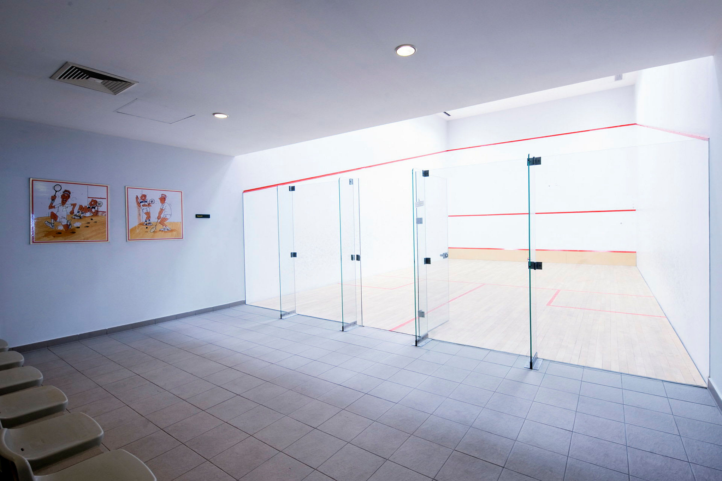 Bild på en squashhall med glasväggar och sittplatser. (AI-genererad text)
