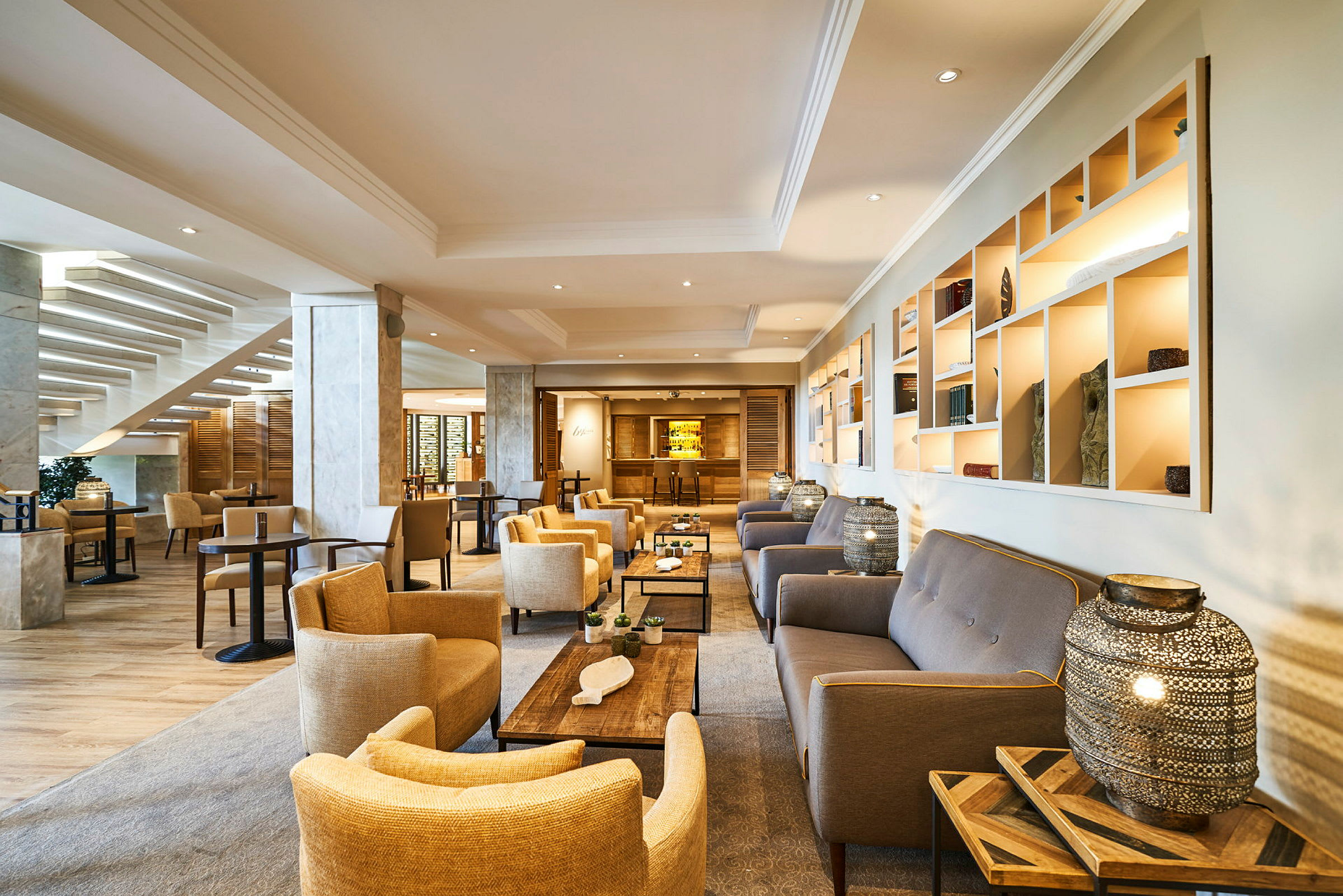 En hotellobby med sittgrupper av fåtöljer och soffor samt bord. (AI-genererad text)