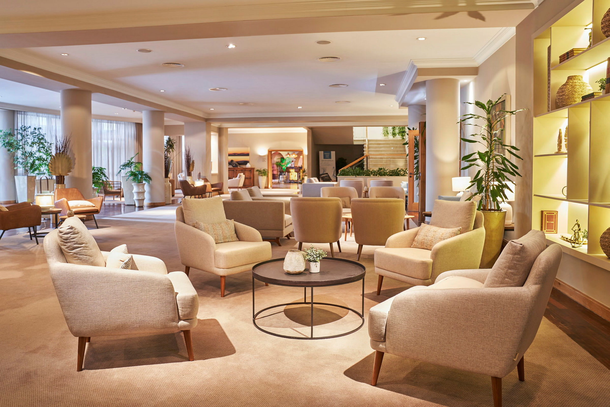 En hotellobby med bekväma stolar och soffor, bord med dekorationer och växter. (AI-genererad text)