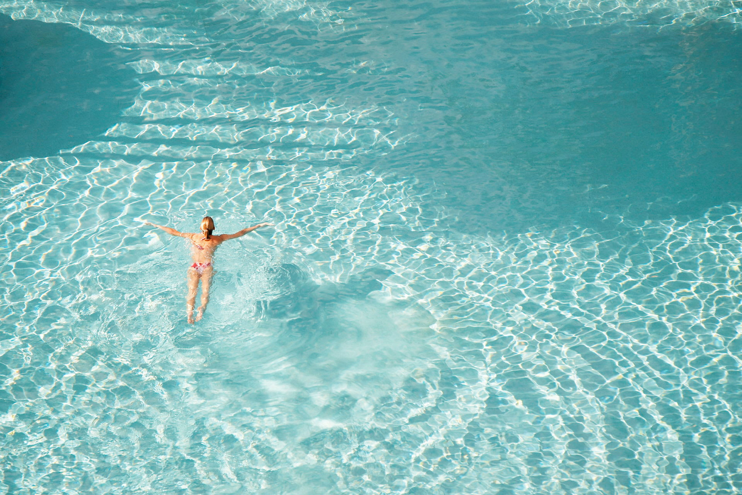 En person simmar i en klarblå pool. (AI-genererad text)
