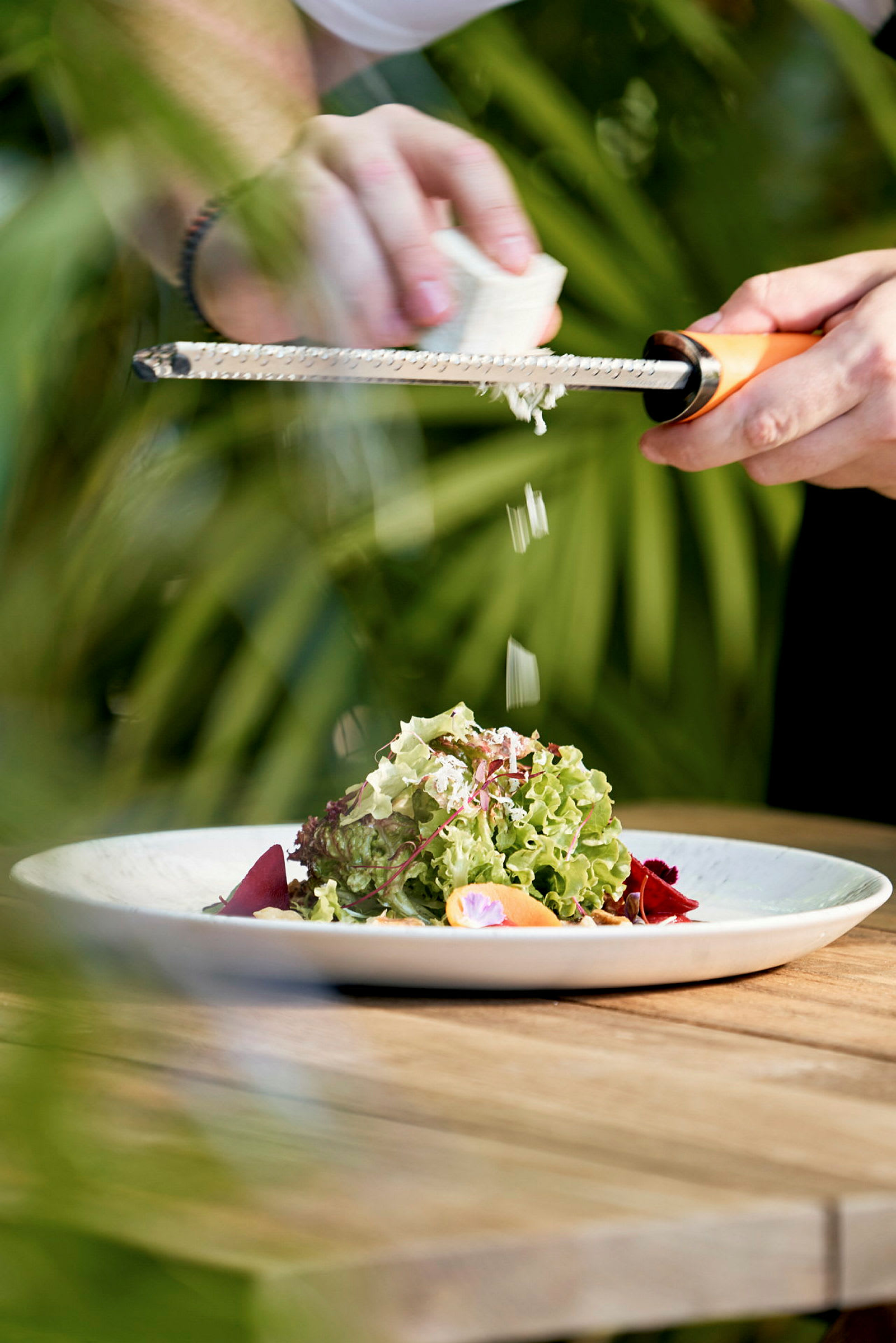 En person river ost över en sallad på en tallrik. (AI-genererad text)