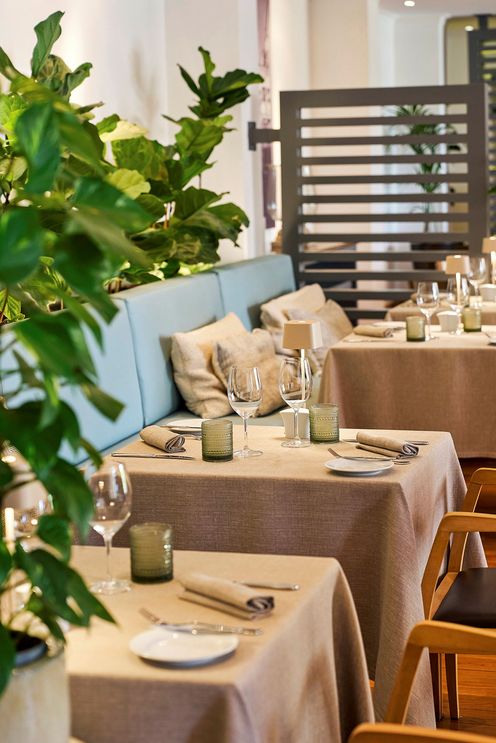 En elegant inredd restaurang med bordduk, tygservetter och gröna växter. (AI-genererad text)