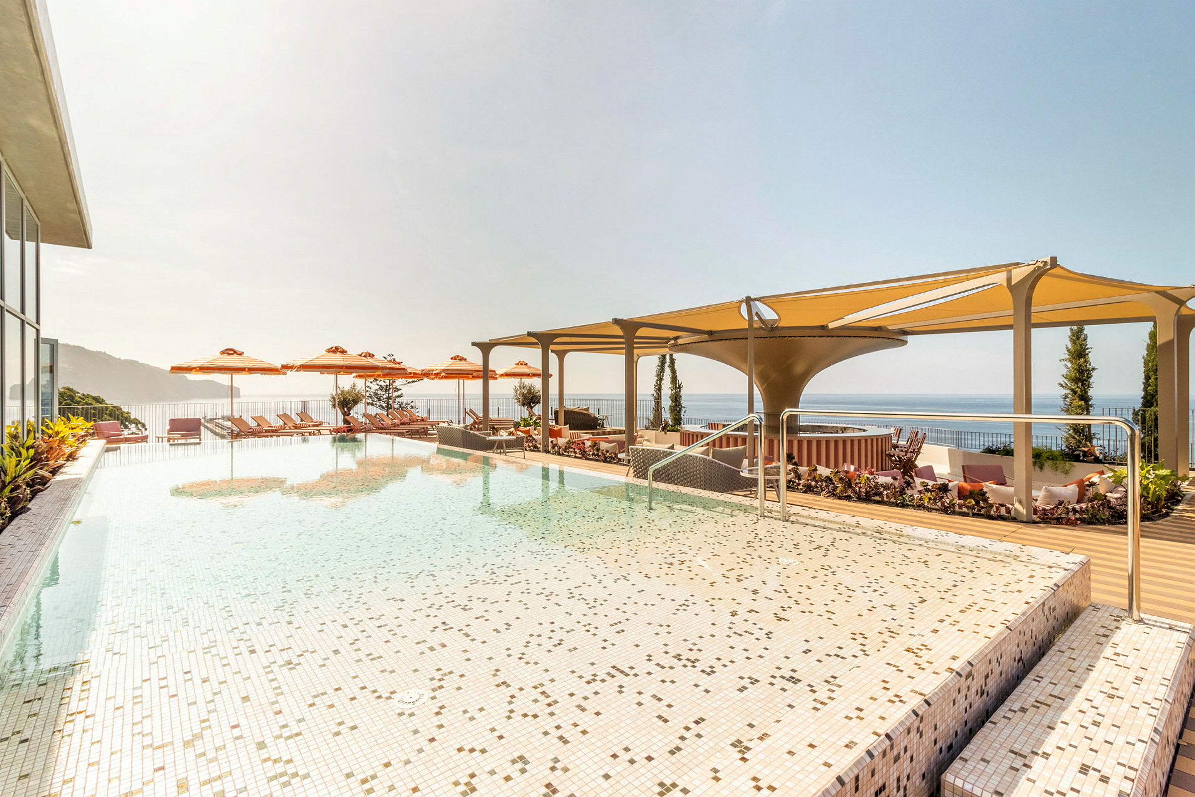 En infinitypool med utsikt över havet, omgiven av solstolar och parasoller. (AI-genererad text)