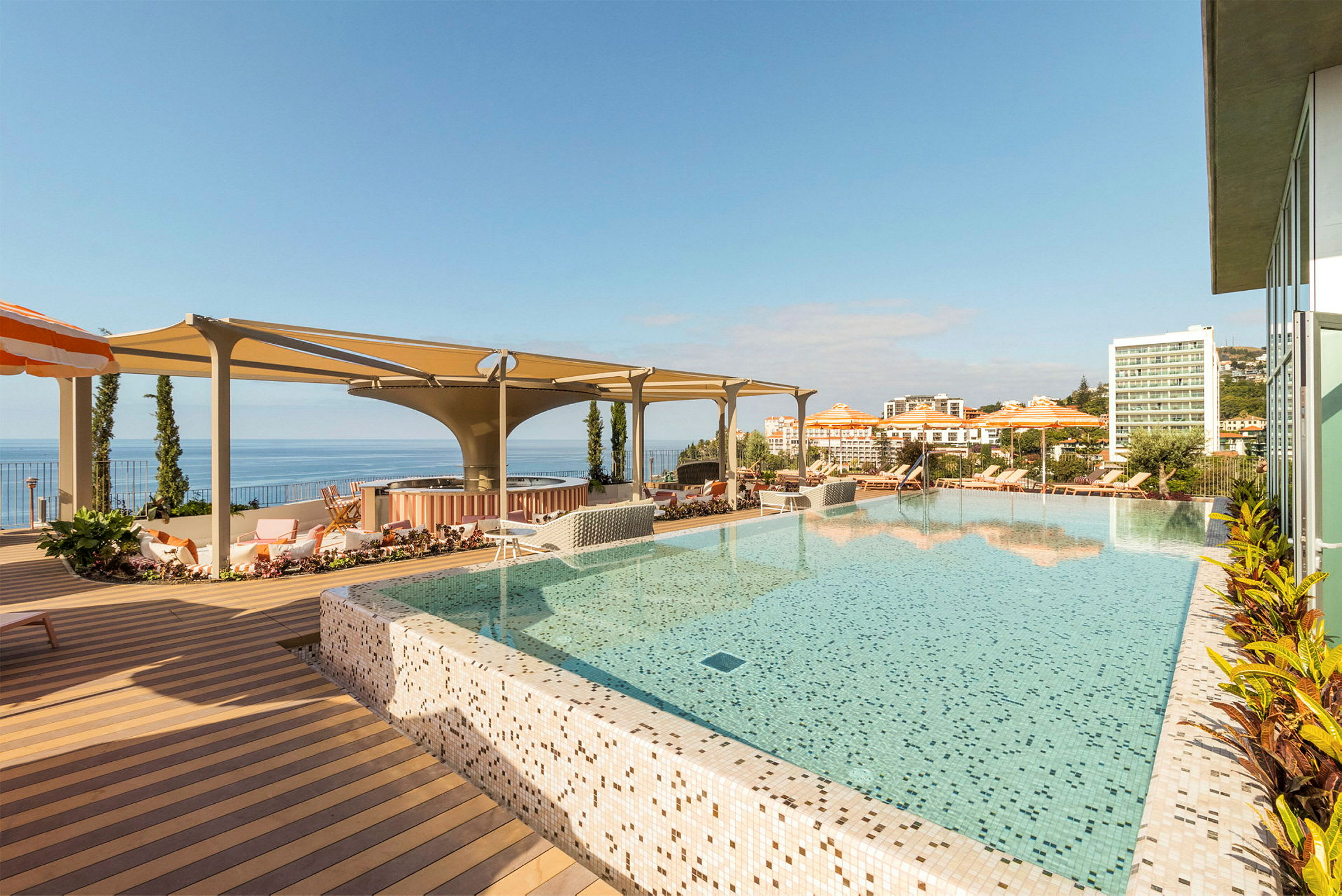 En infinitypool med utsikt över havet och hotellbyggnader i bakgrunden. (AI-genererad text)