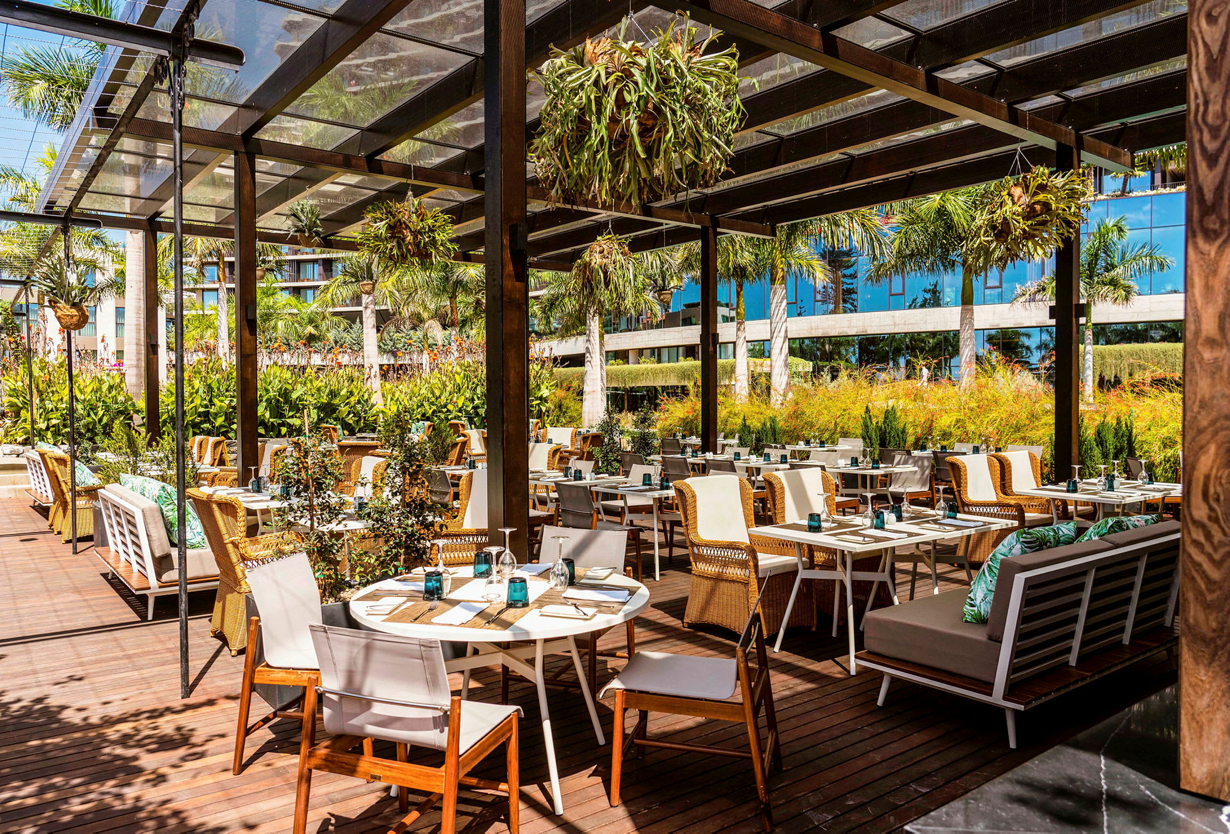 Utomhusrestaurang med träbord och stolar under en pergola. (AI-genererad text)