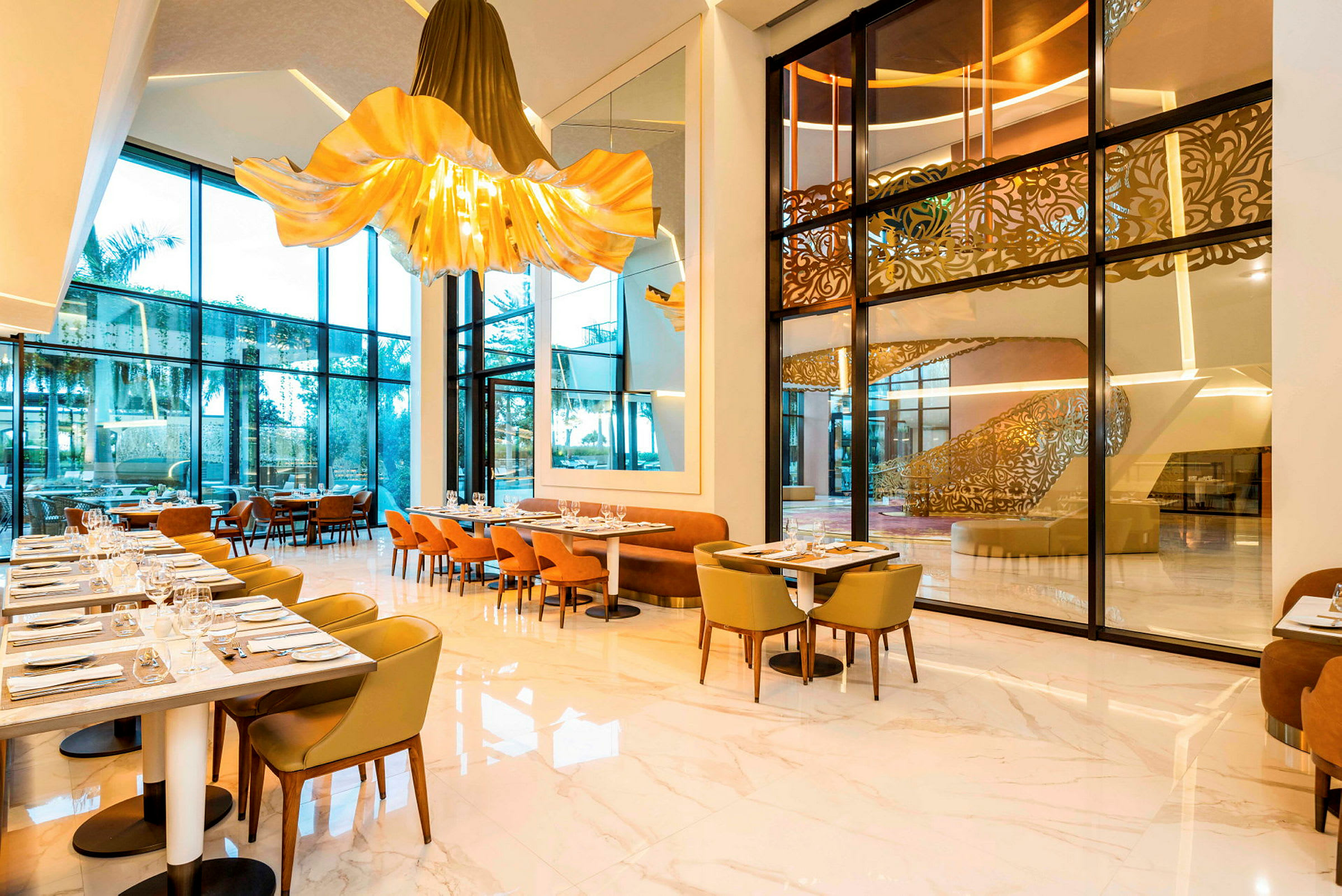 Modern restaurang med stora glasfönster, eleganta stolar och belysning. (AI-genererad text)