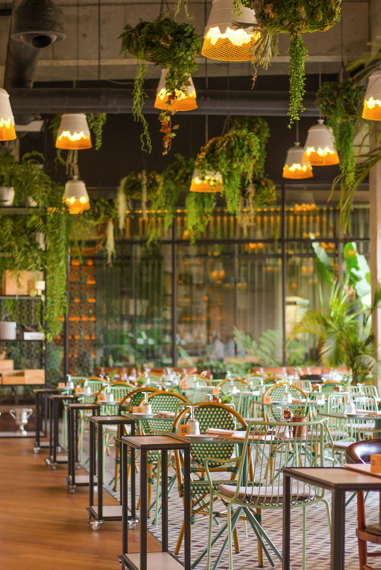 Interiör av en restaurang med gröna sittplatser och växter i taket. (AI-genererad text)