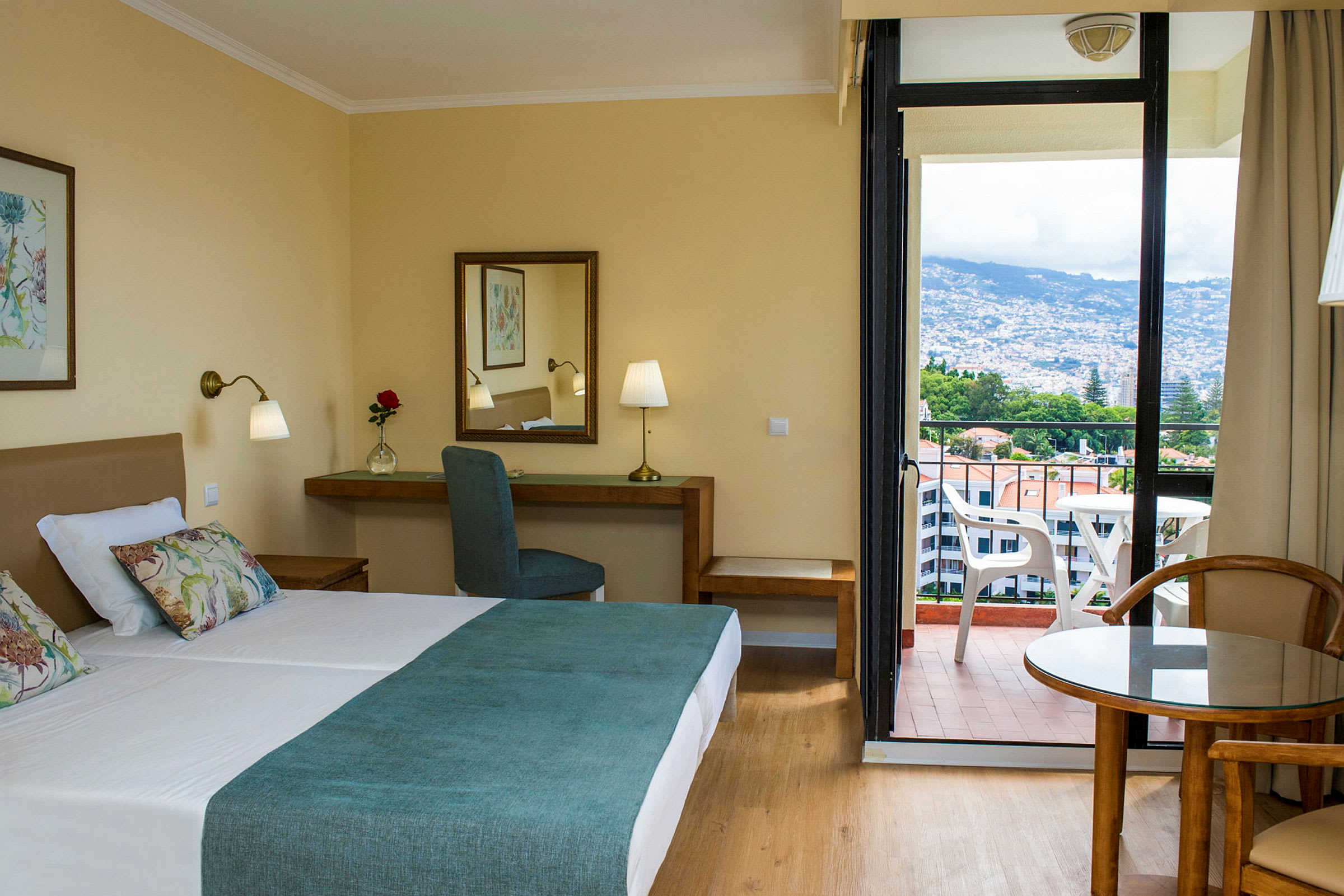 Hotellrum med dubbelsäng, skrivbord och balkong med utsikt. (AI-genererad text)