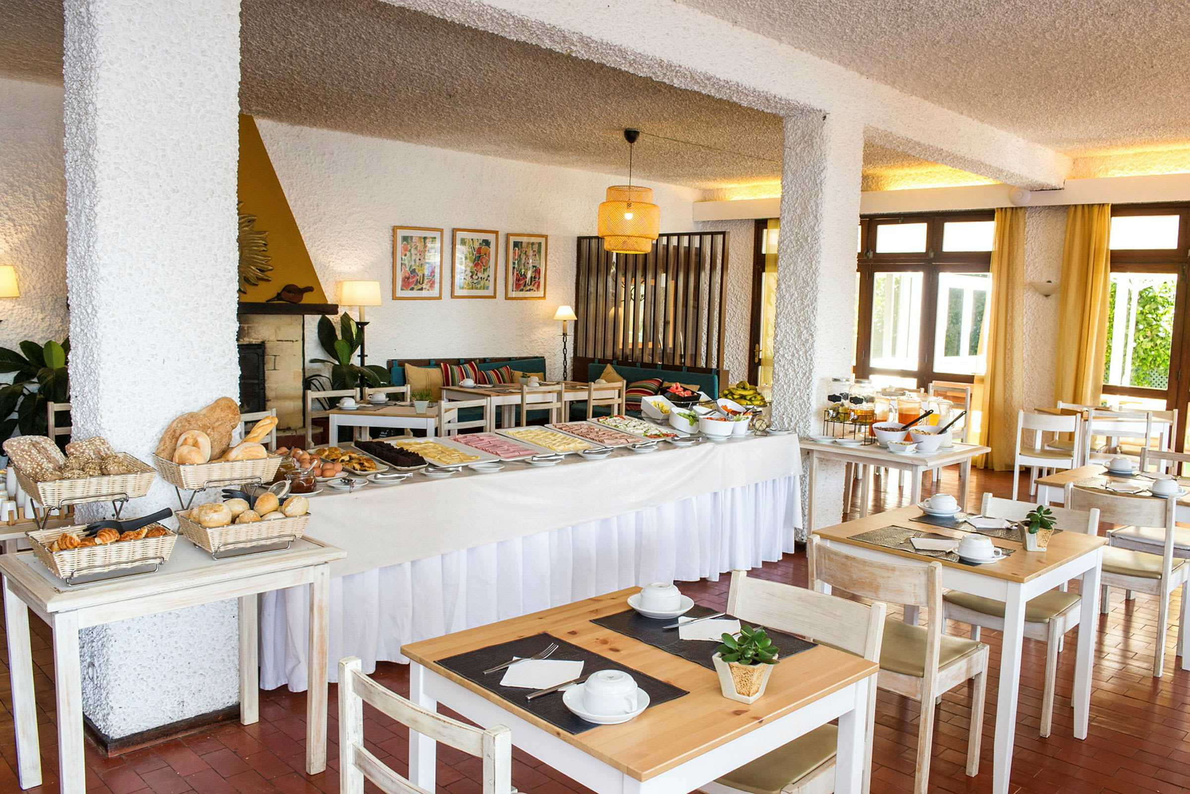 Ett hotellrestaurangområde med ett frukostbuffébord och sittplatser. (AI-genererad text)