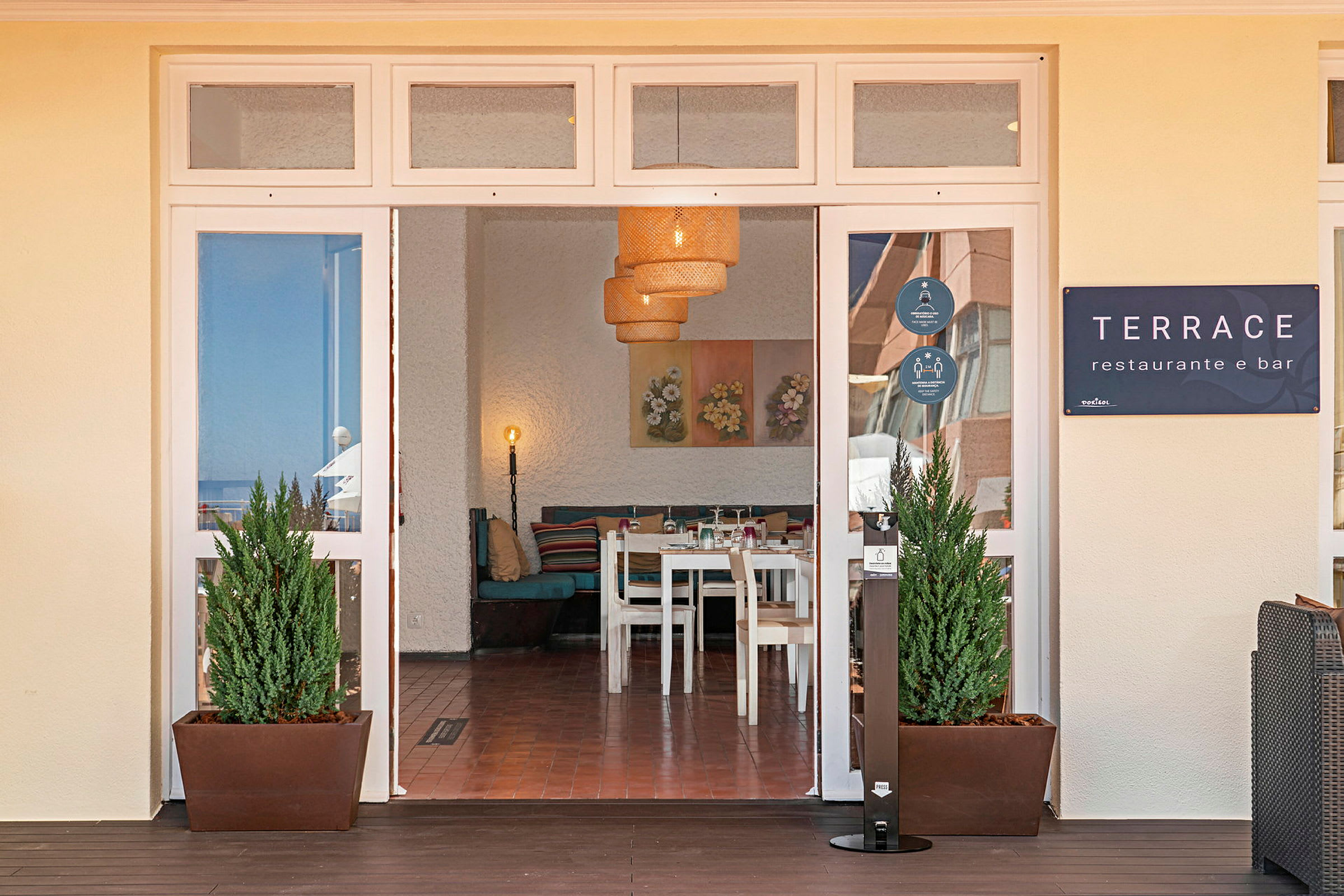 Entrén till en restaurang med namnet Terrace, inomhus syns bord och stolar samt dekorerade väggar. (AI-genererad text)