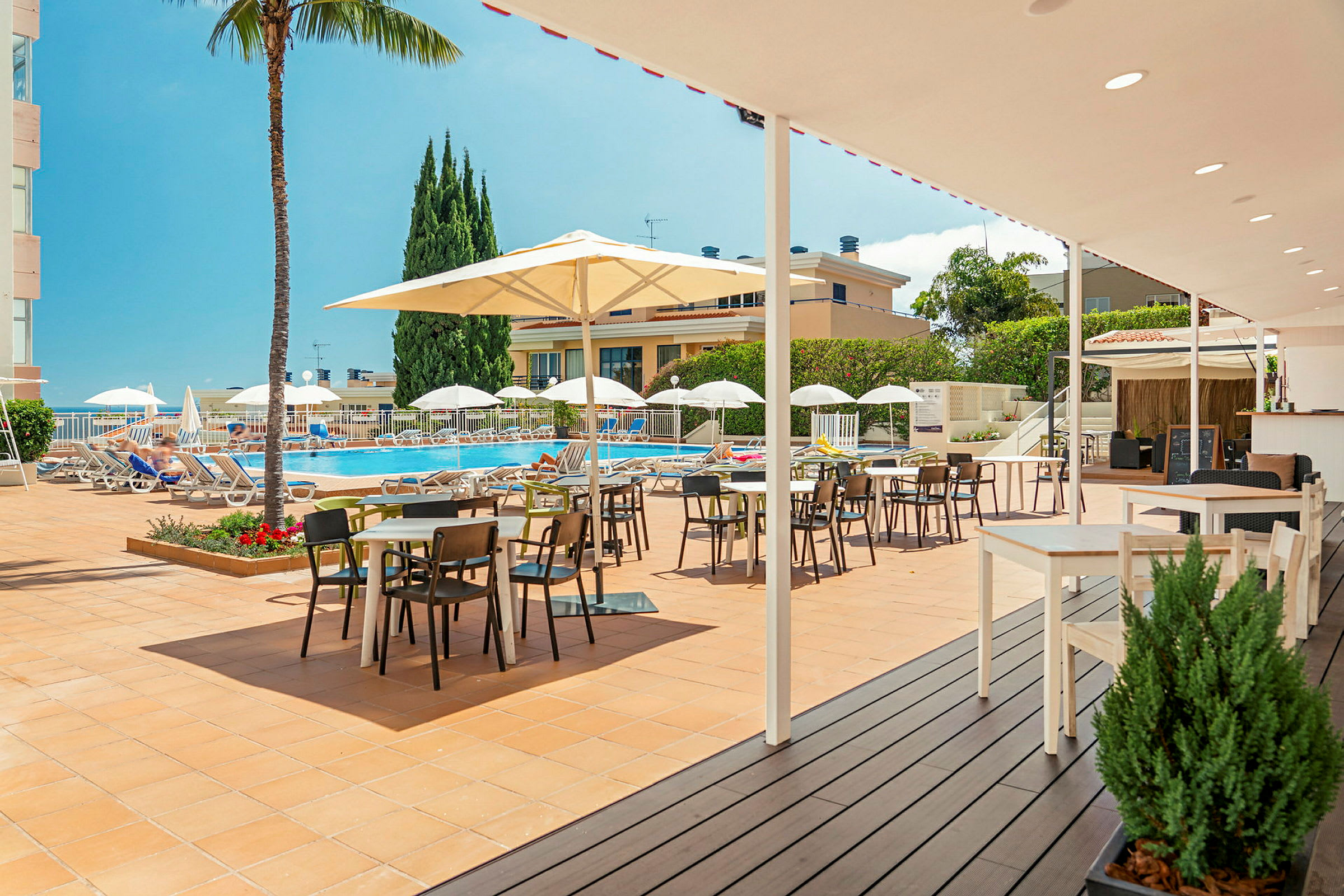 Bild av en solig terrass med bord och stolar nära en pool. (AI-genererad text)