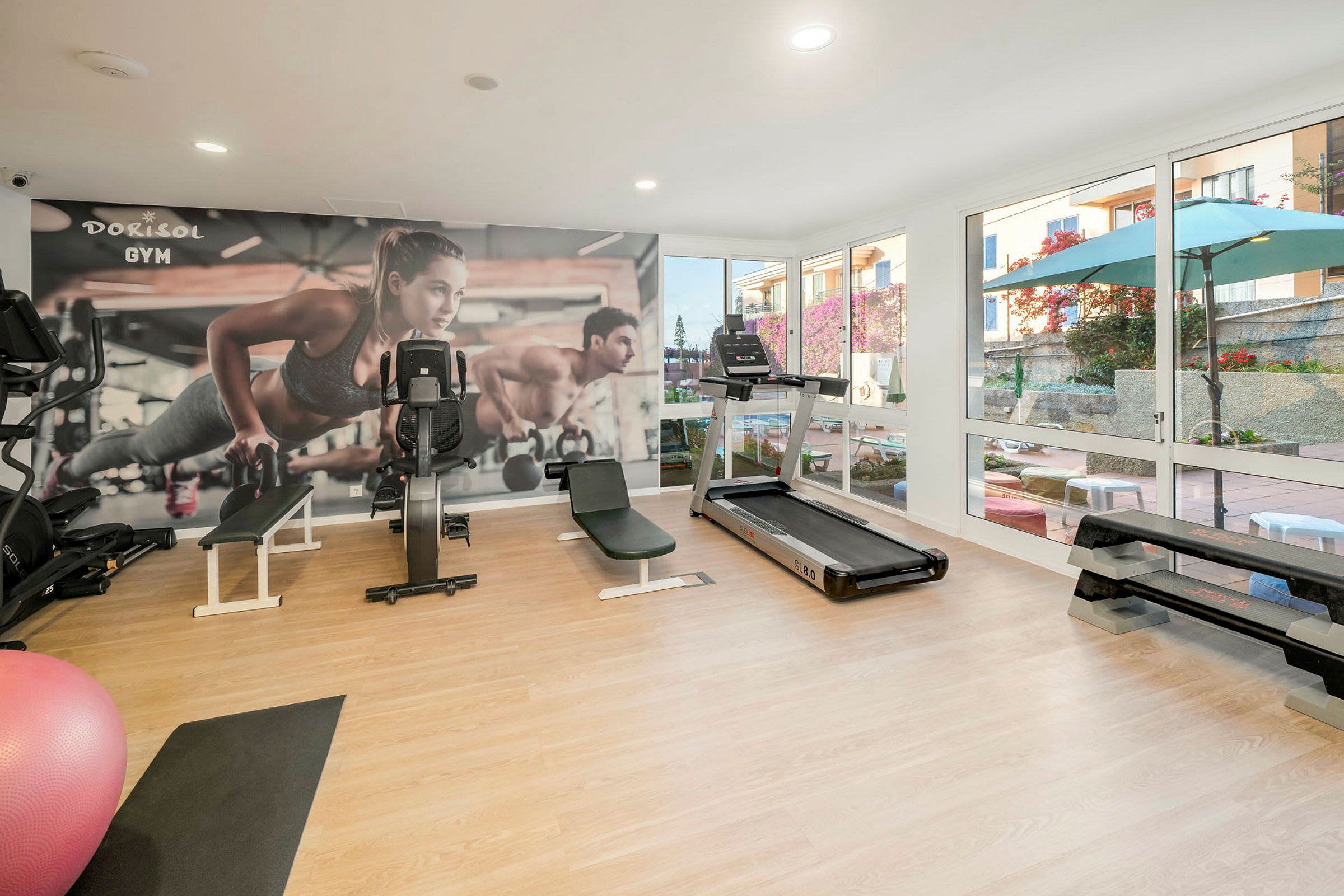 Ett ljust gym med träningsutrustning och en vägg med fototapet. (AI-genererad text)