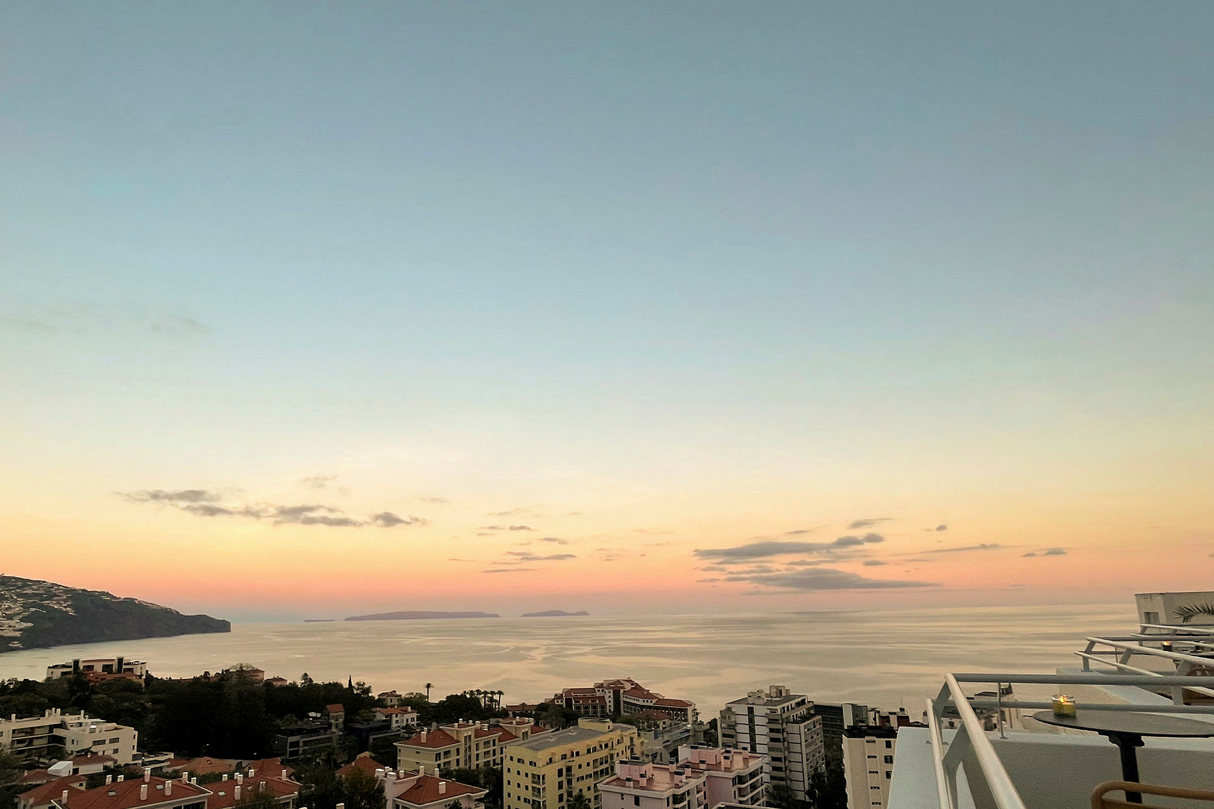 Bild av en kuststad med byggnader i förgrunden och havet i bakgrunden under solnedgång. (AI-genererad text)