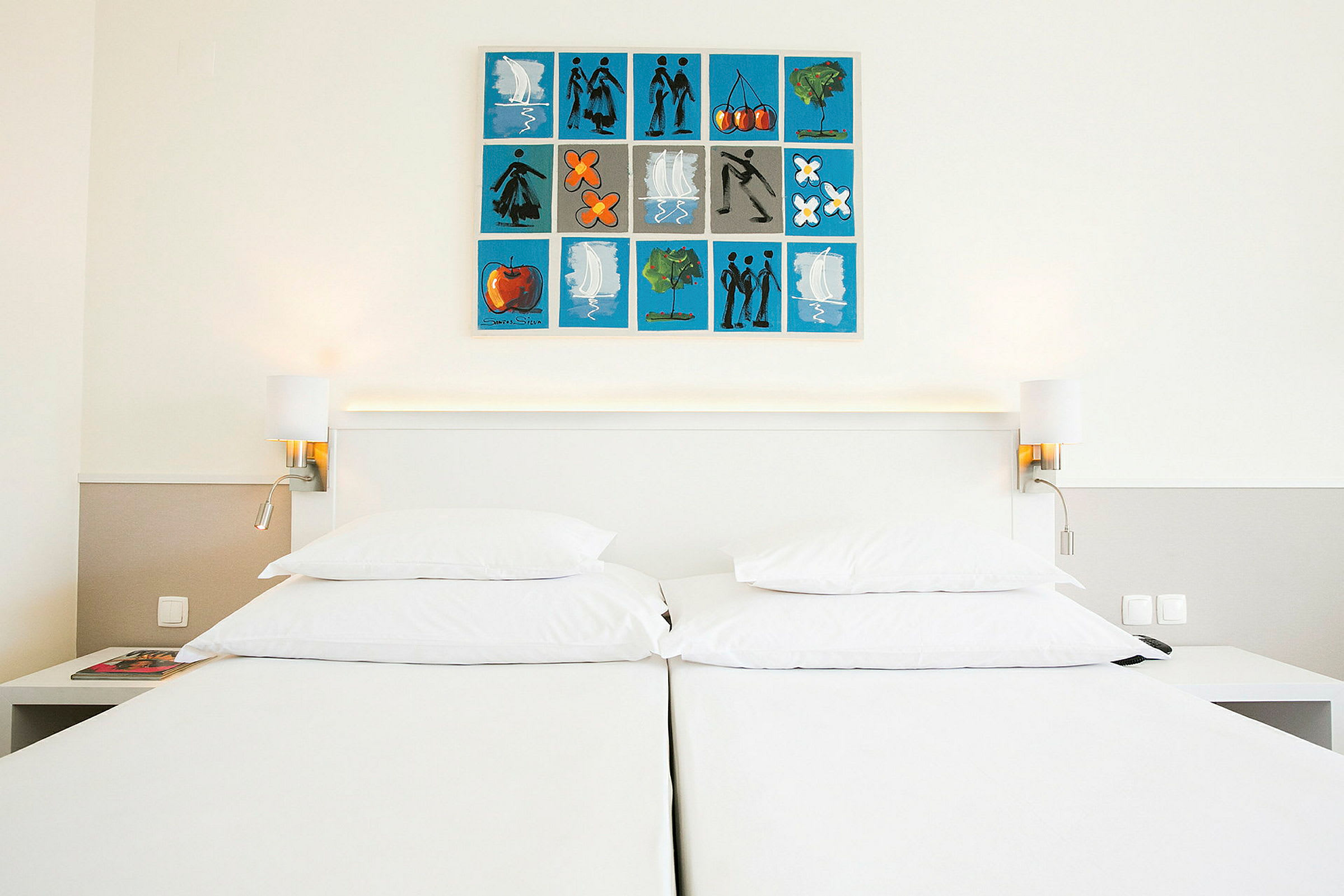 En hotellsäng med vita sängkläder, två sängbord och en målad tavla på väggen ovanför sängen. (AI-genererad text)