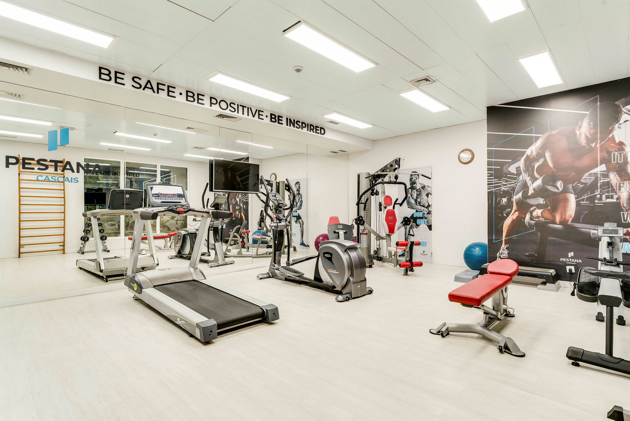 Gym med olika träningsmaskiner och spegelvägg. (AI-genererad text)
